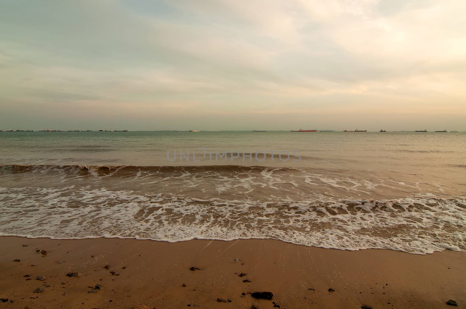 Singapore East Coast Park.View on the beach and ocean at sunset.
Far on the horizon Ships moored at the road.Horizontal view.
