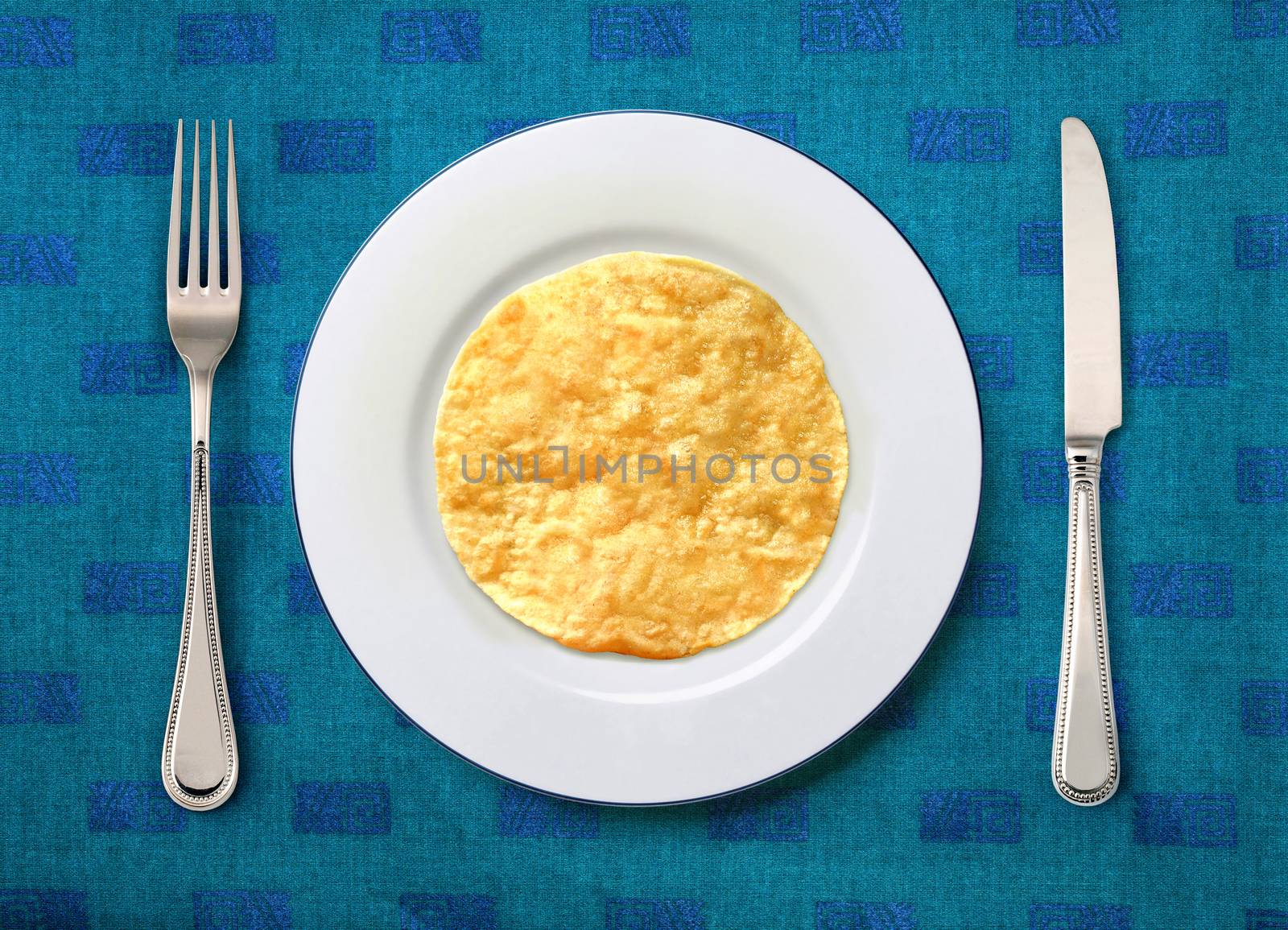 round white plate with slapjack, knife and fork on table