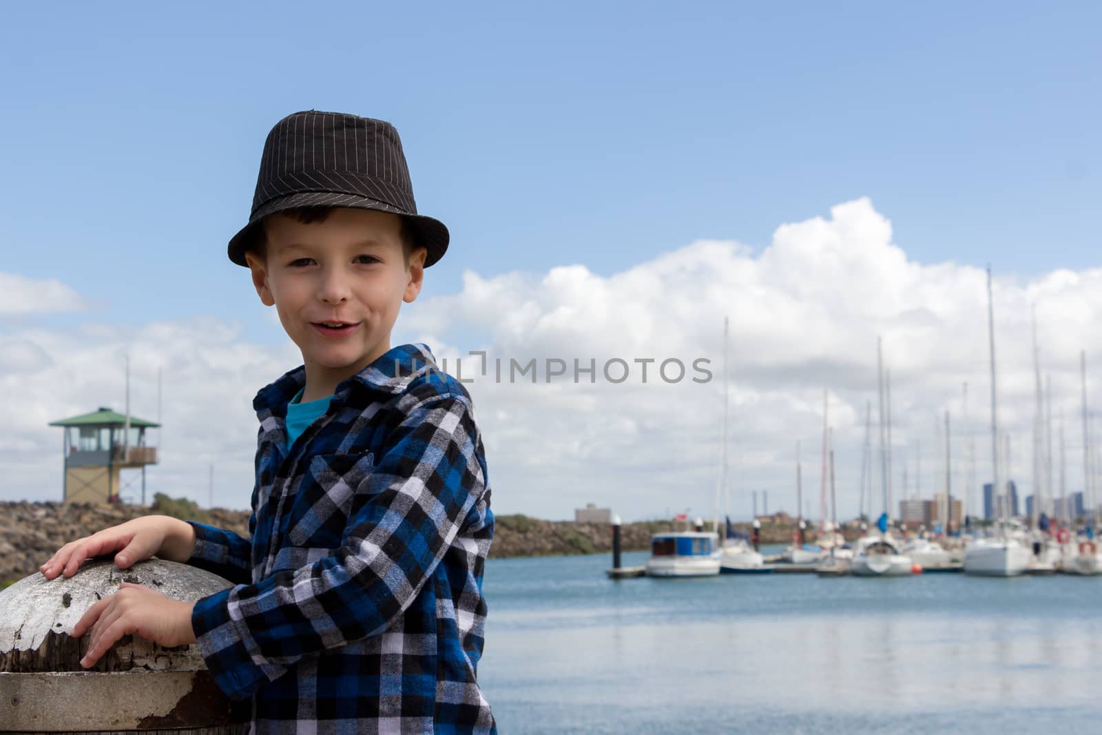 A young boy smiling at a marina.