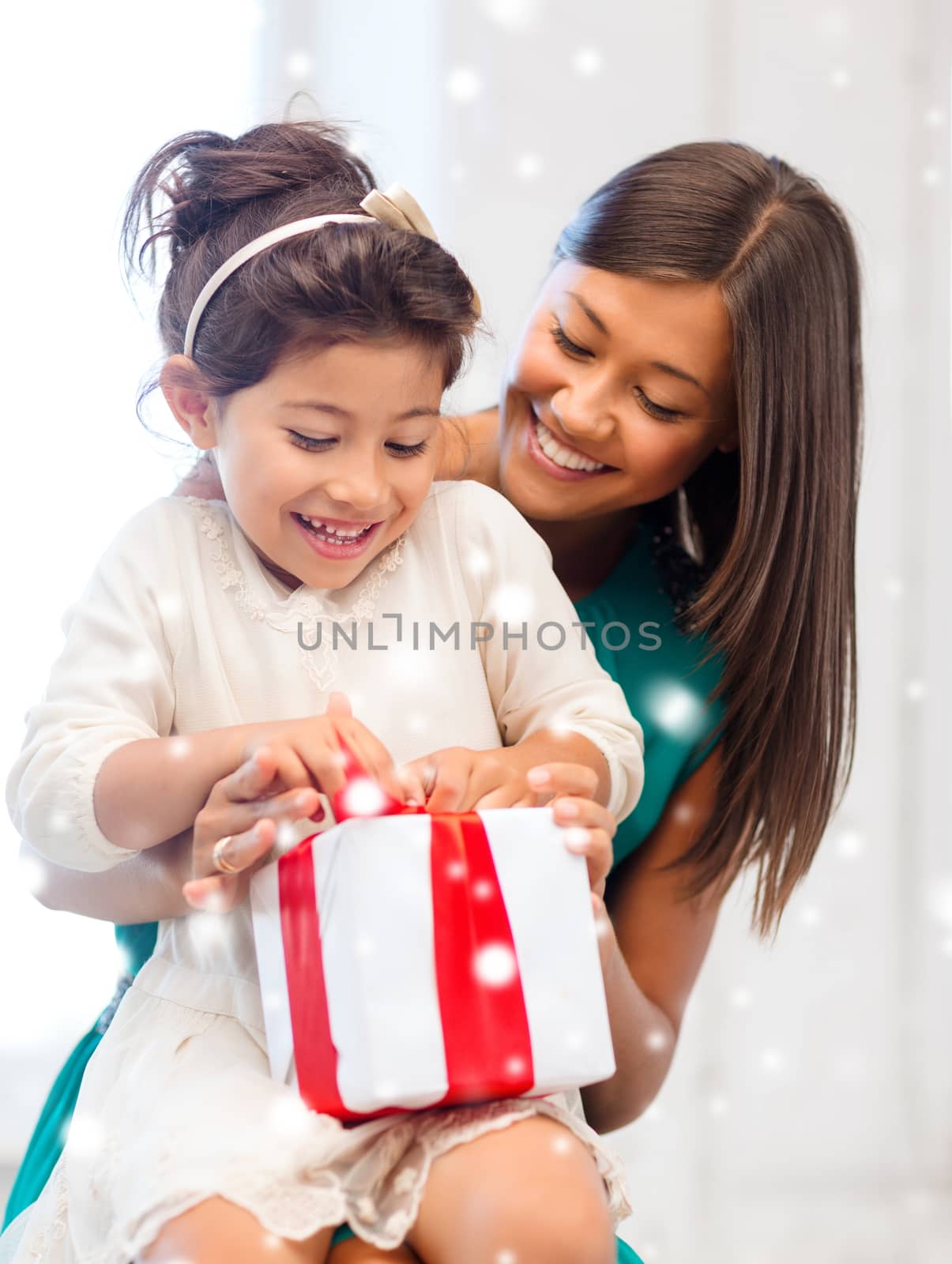 christmas, holidays, family and people concept - happy mother and child girl with gift box at home