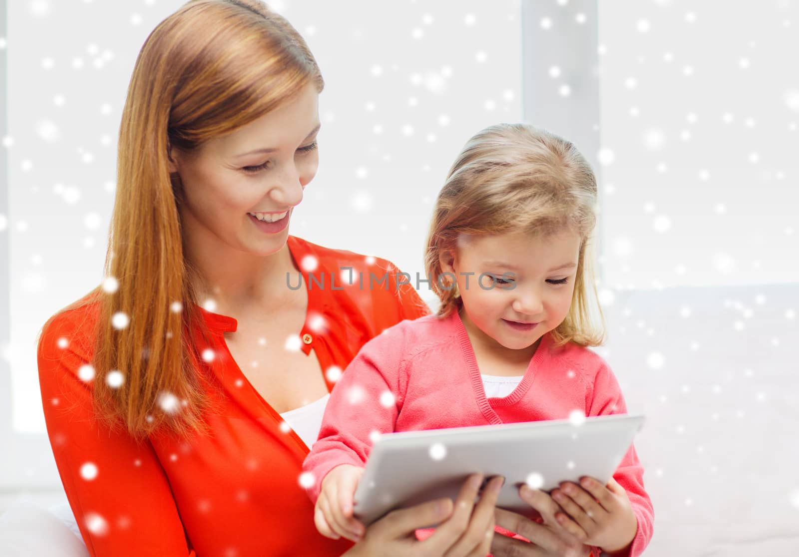 family, childhood, holidays, technology and people concept - happy mother and daughter with tablet pc computer at home