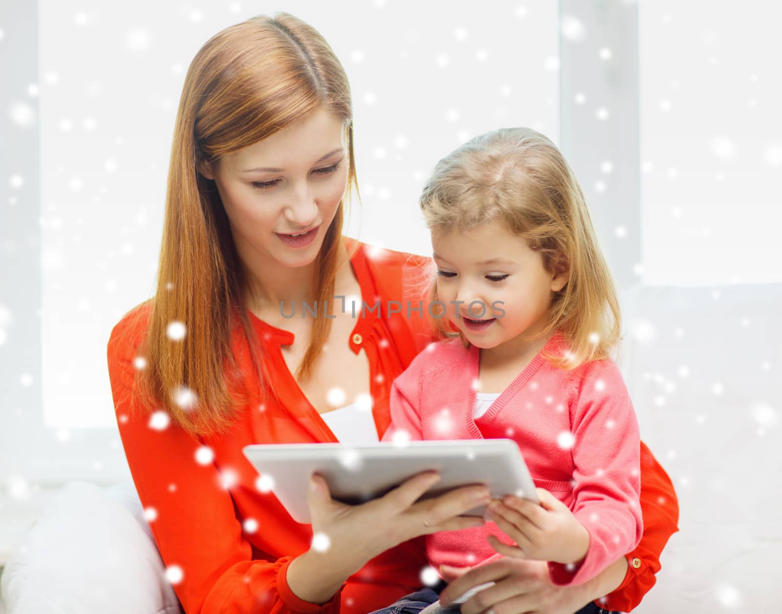 family, childhood, holidays, technology and people concept - happy mother and daughter with tablet pc computer at home