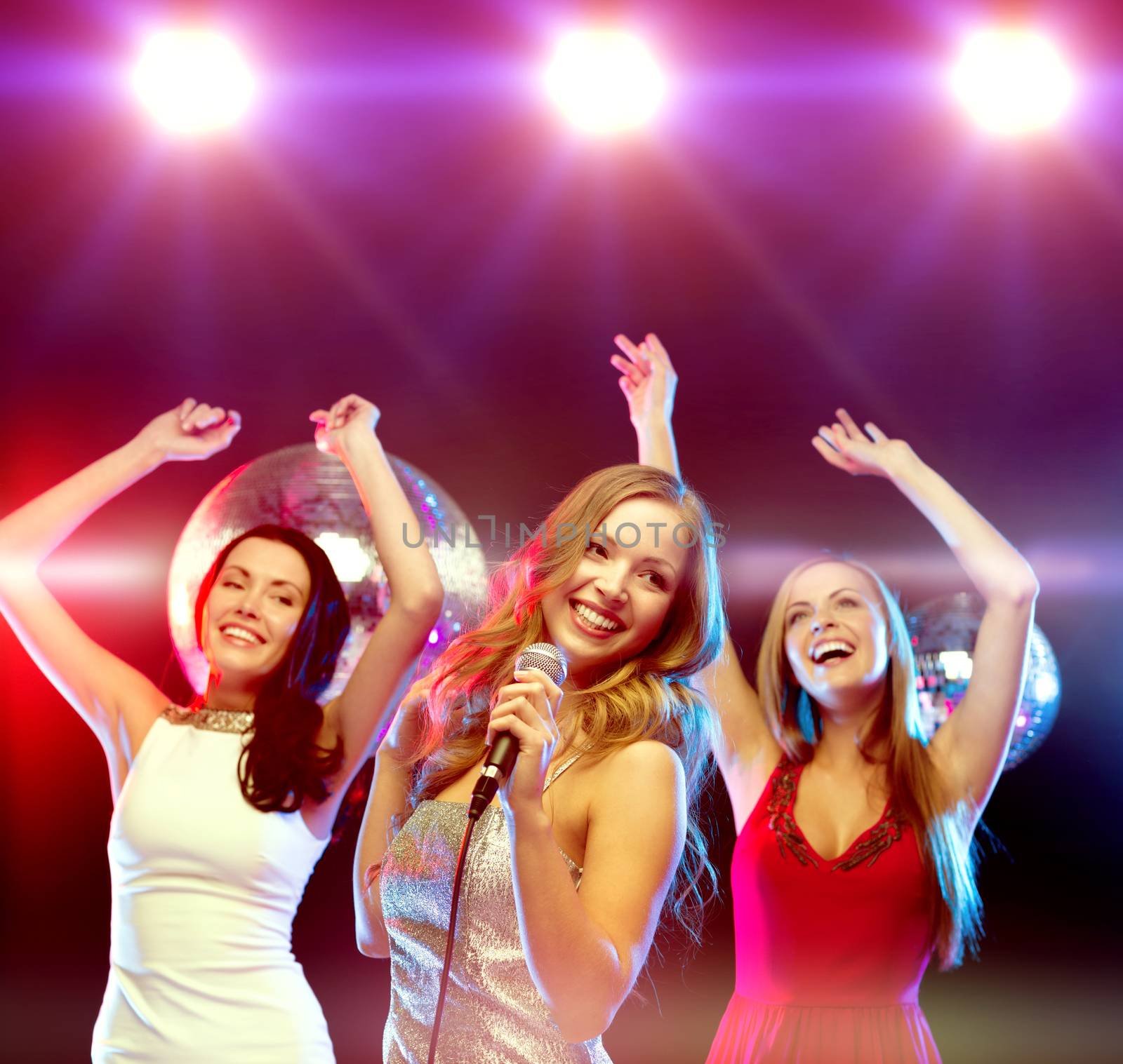 three smiling women dancing and singing karaoke by dolgachov