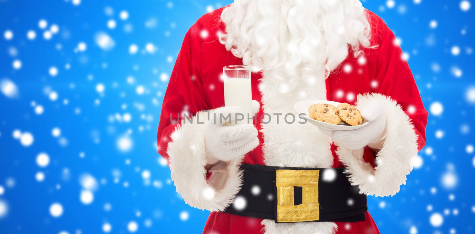 christmas, holidays, food, drink and people concept - close up of santa claus with glass of milk and cookies over blue snowy background