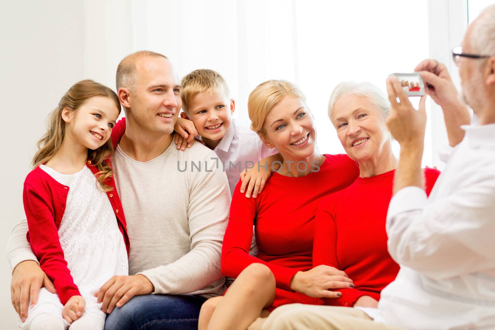 family, holidays, generation, christmas and people concept - smiling family with camera photographing and sitting on couch at home