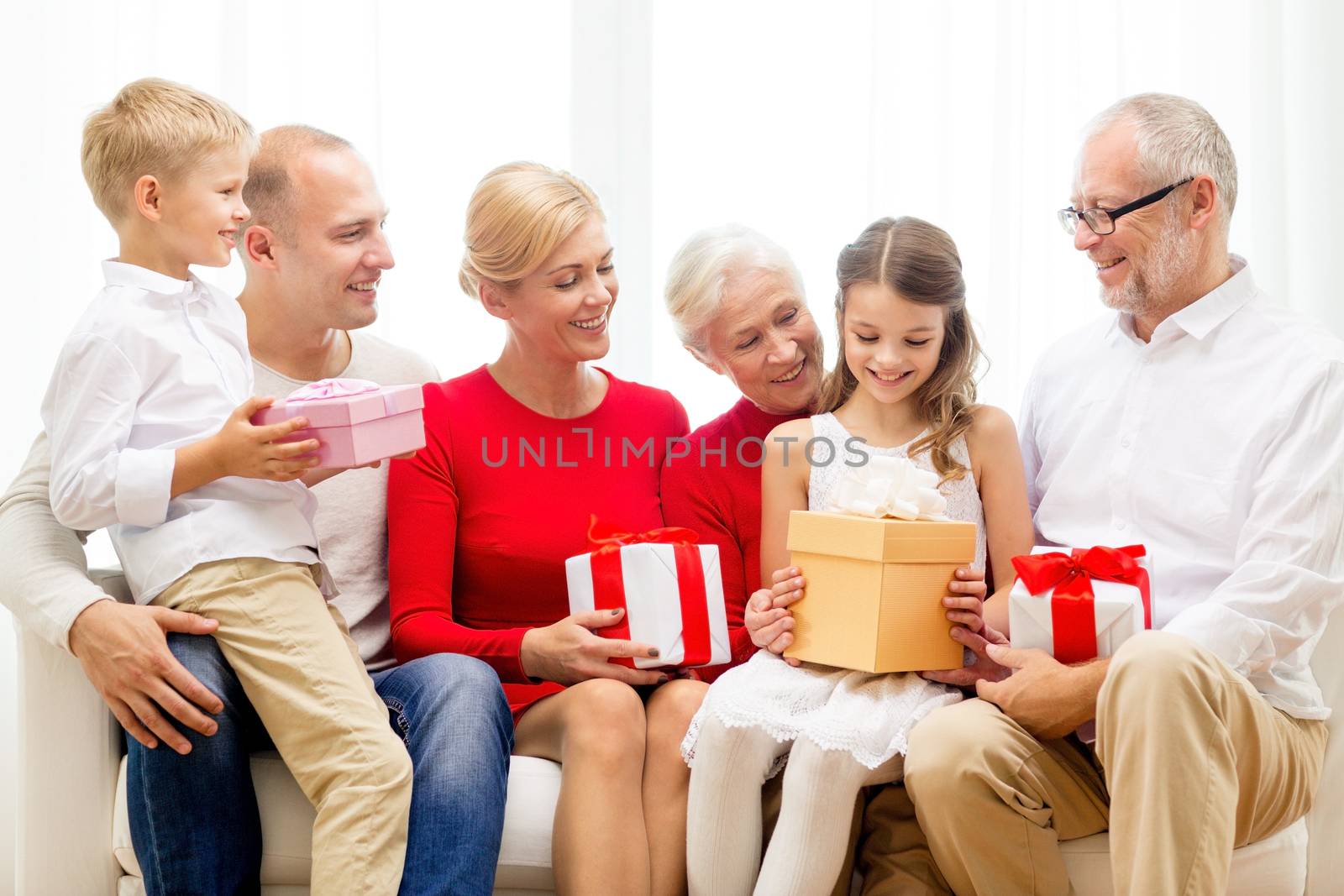 family, holidays, generation, christmas and people concept - smiling family with gift boxes sitting on couch at home