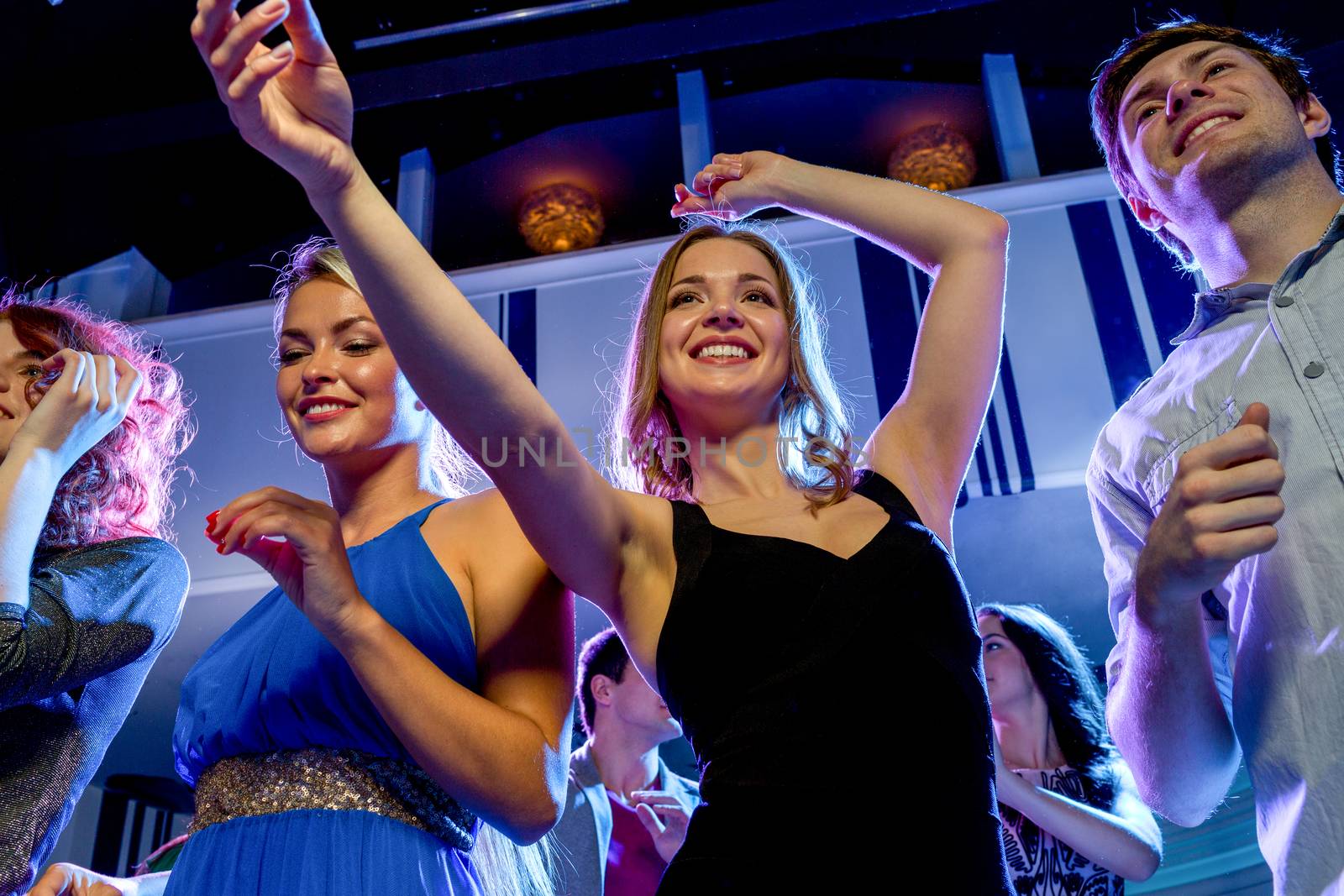 smiling friends dancing in club by dolgachov