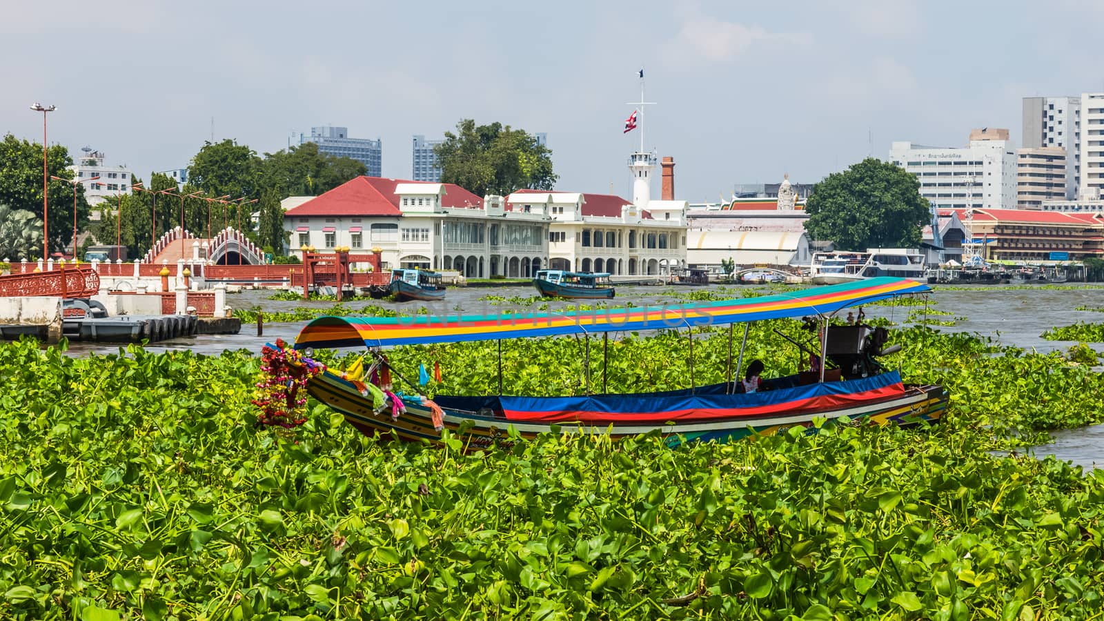 Tourist boat on the Chao Phraya River on the background of a harbor. City of Bangkok occupies 1.568 square kilometers with a population of 8 million inhabitants.