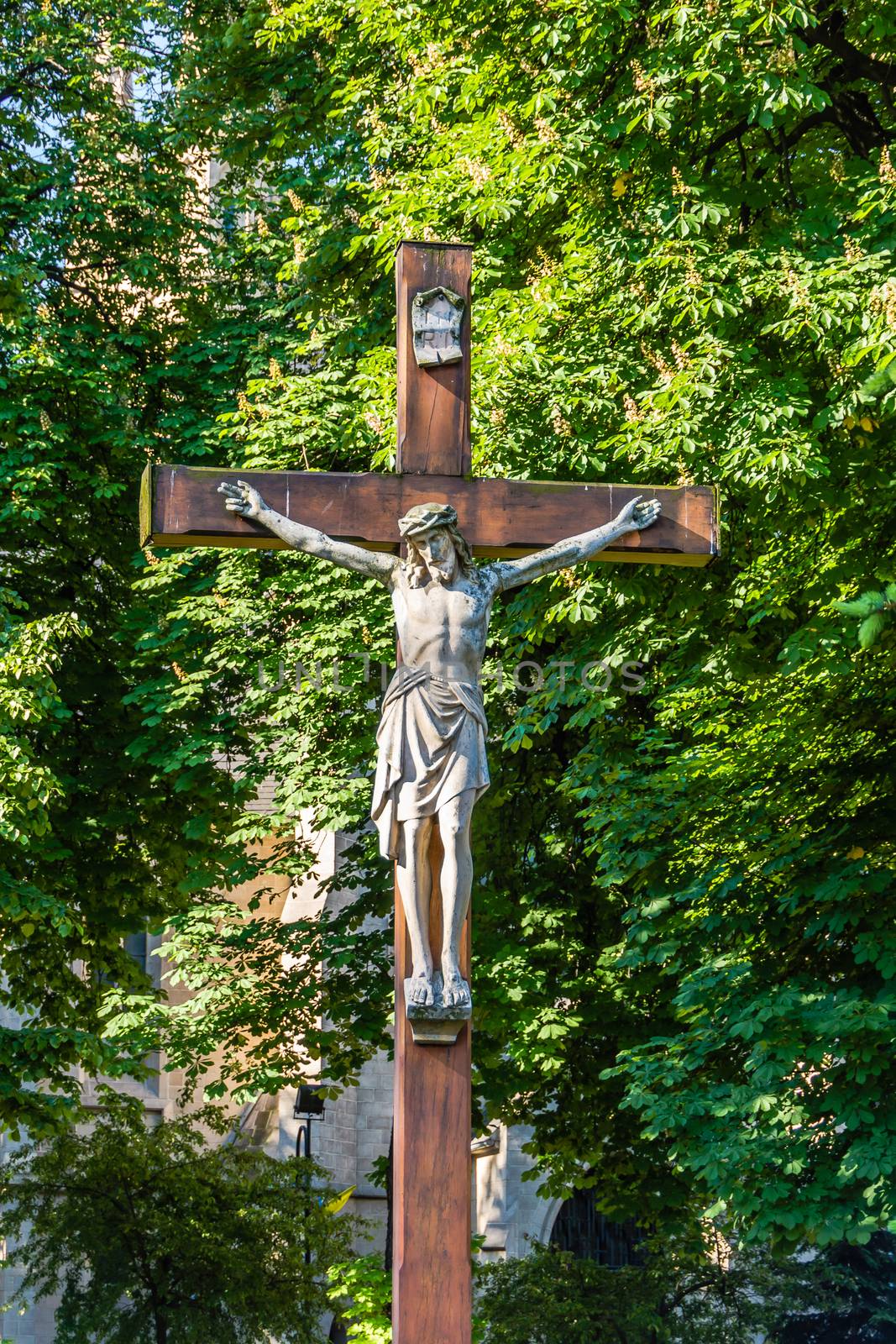 Statue of Jesus Christ crucified. In the very background the Church of the Immaculate Conception of the Blessed Virgin Mary in Katowice, Silesia region, Poland.