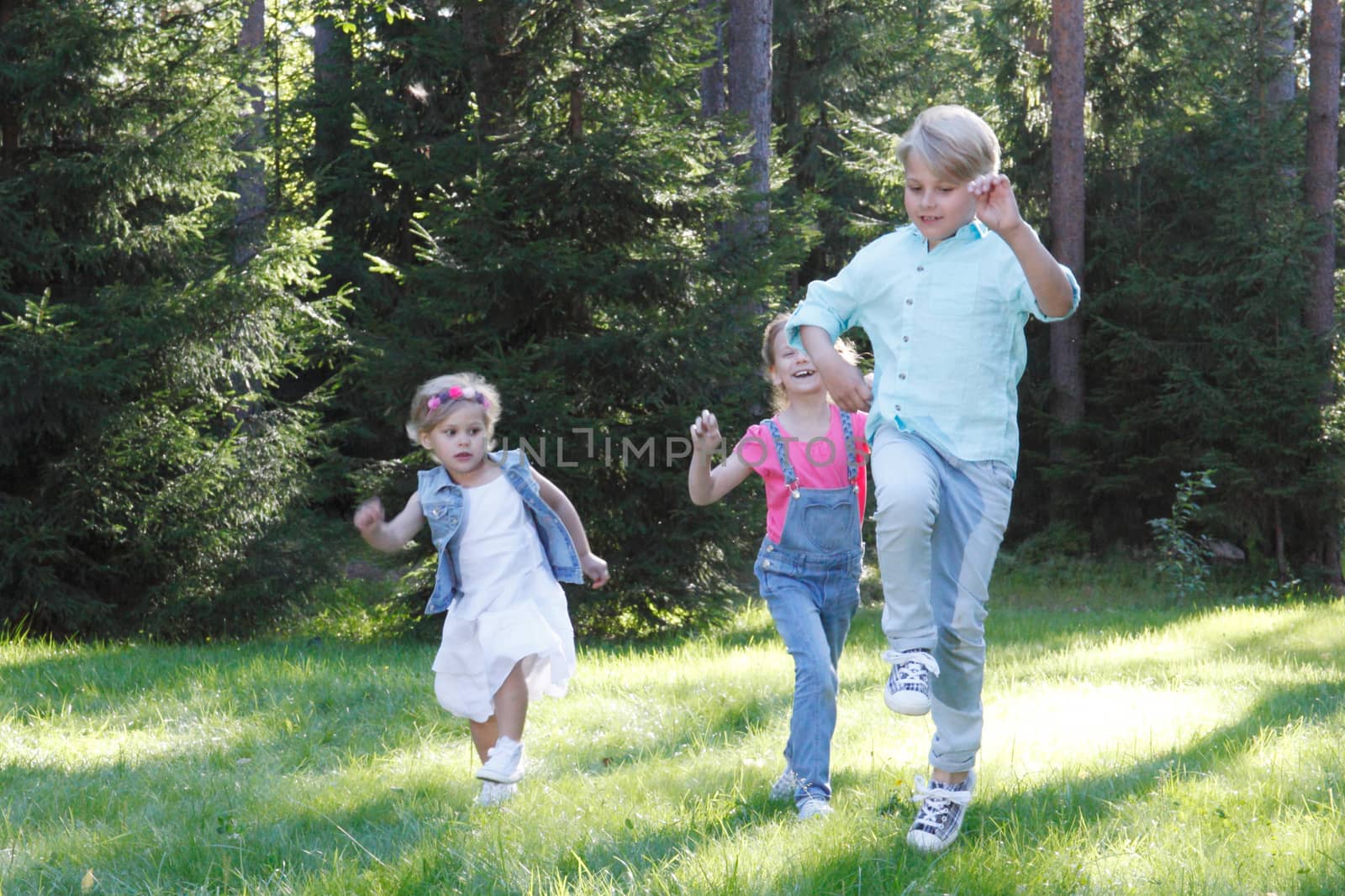 Group of young children running towards camera in park