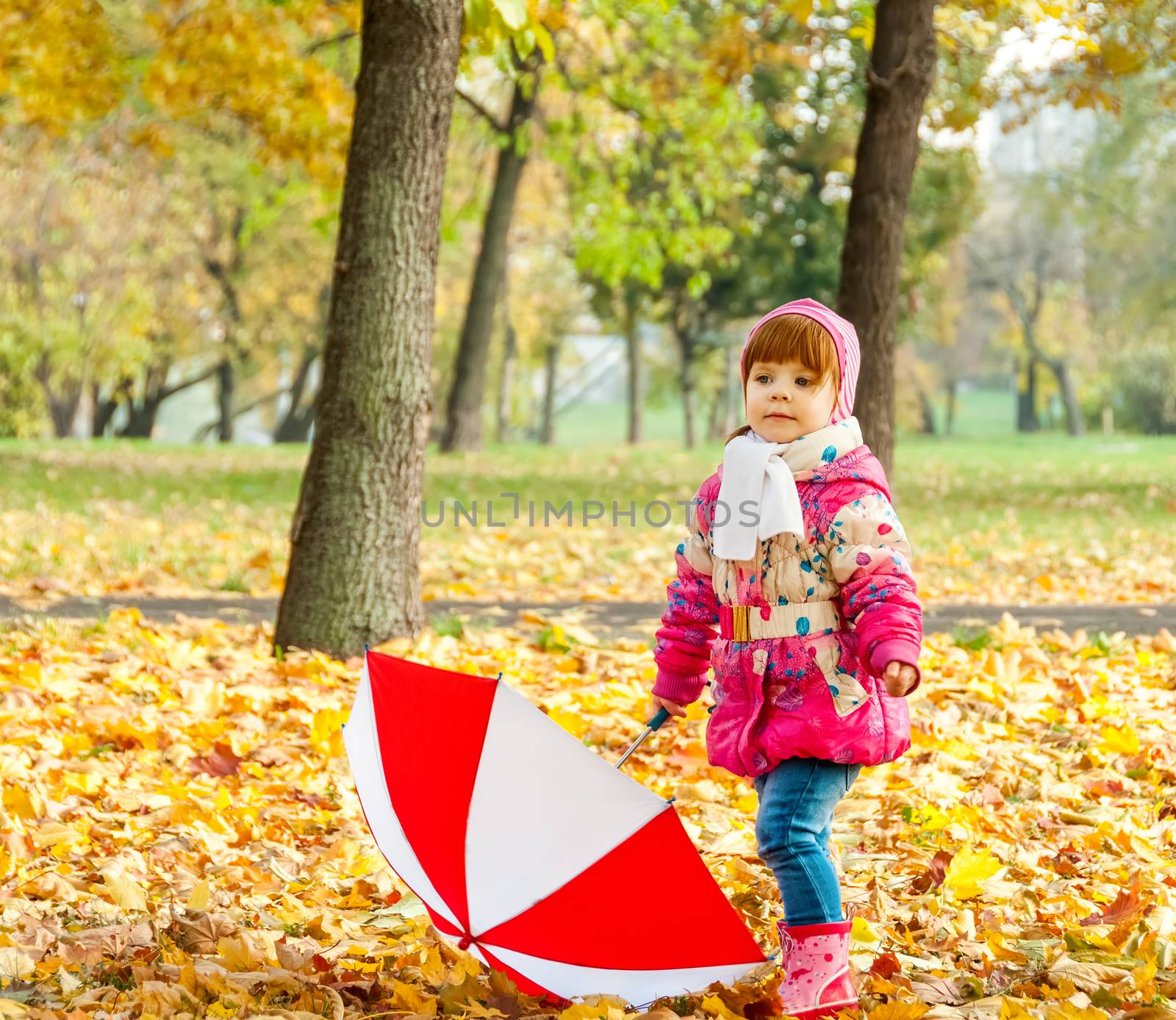 A little girl walking in the park with an umbrella