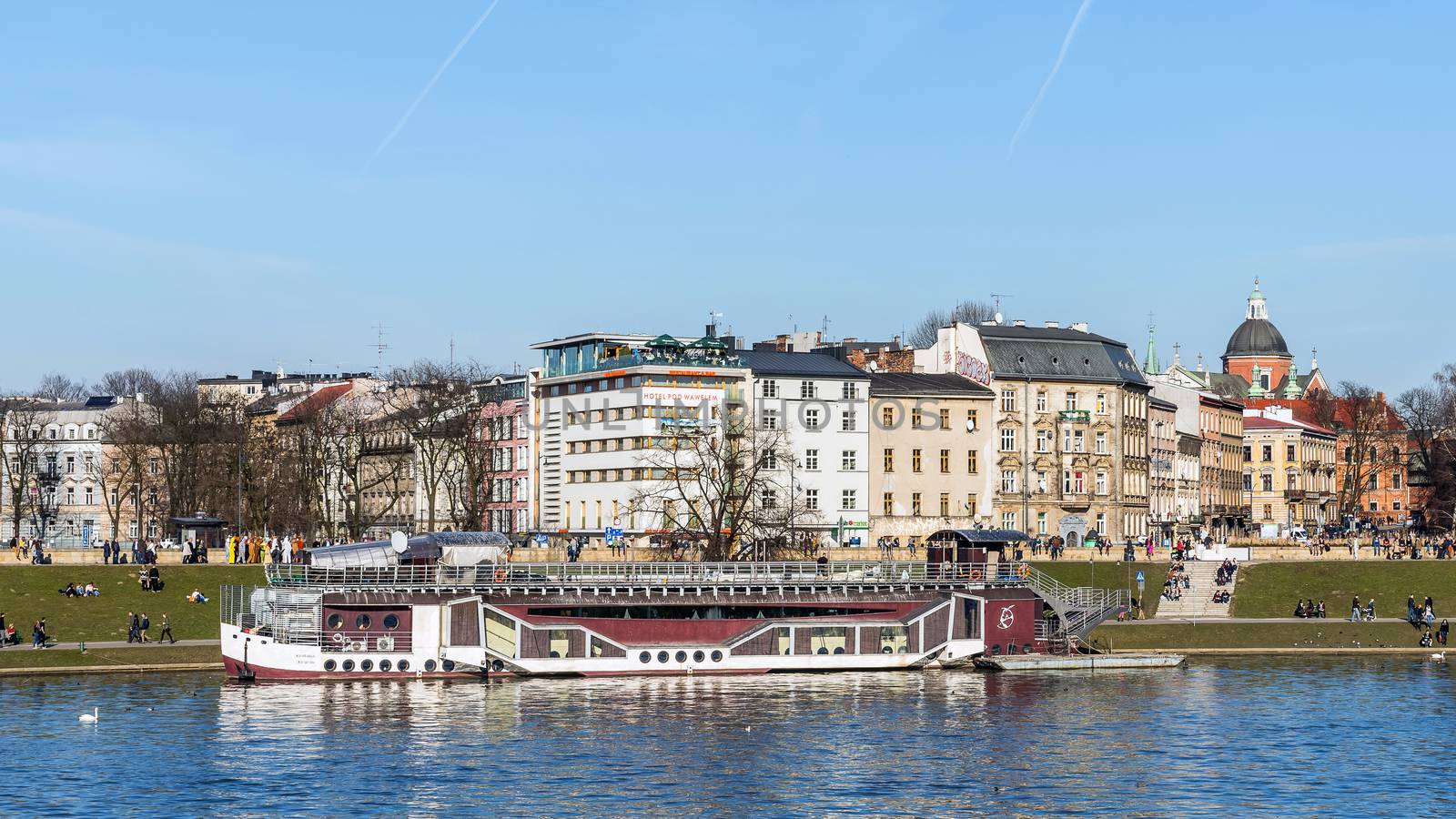 Pleasure boat moored by the boulevard at the foot of the Wawel castle hill in Cracow, historical seat of Polish kings, the most popular destination in Poland.