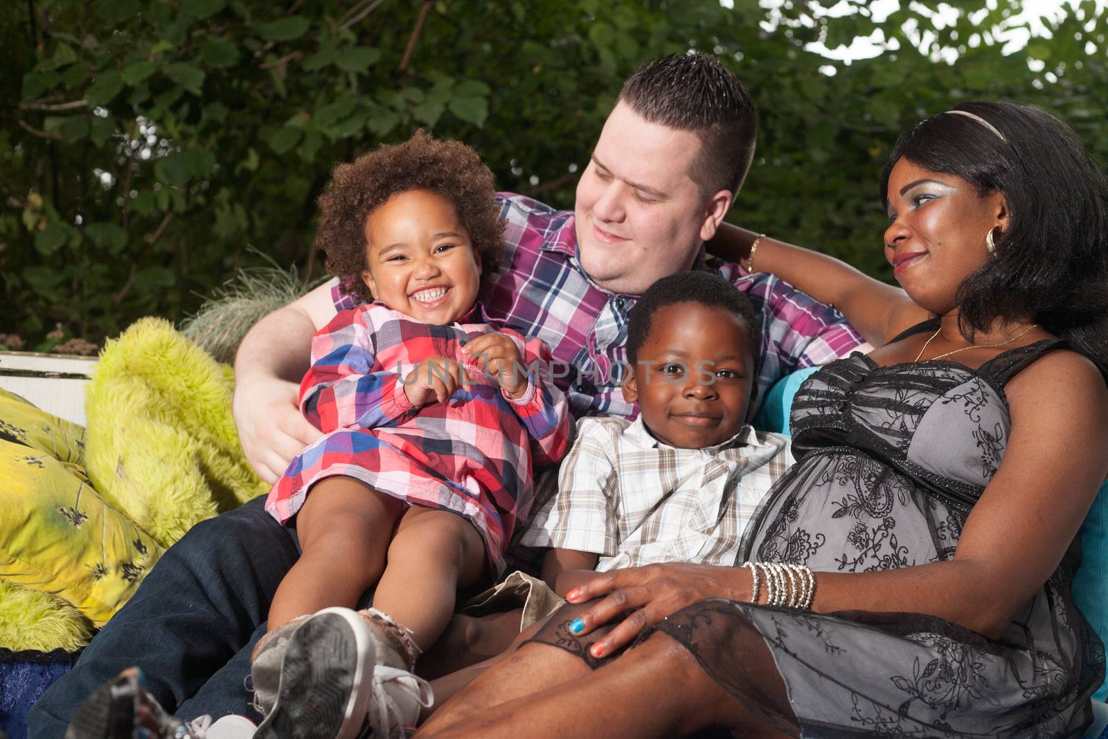 African family is sitting on the couch in the garden