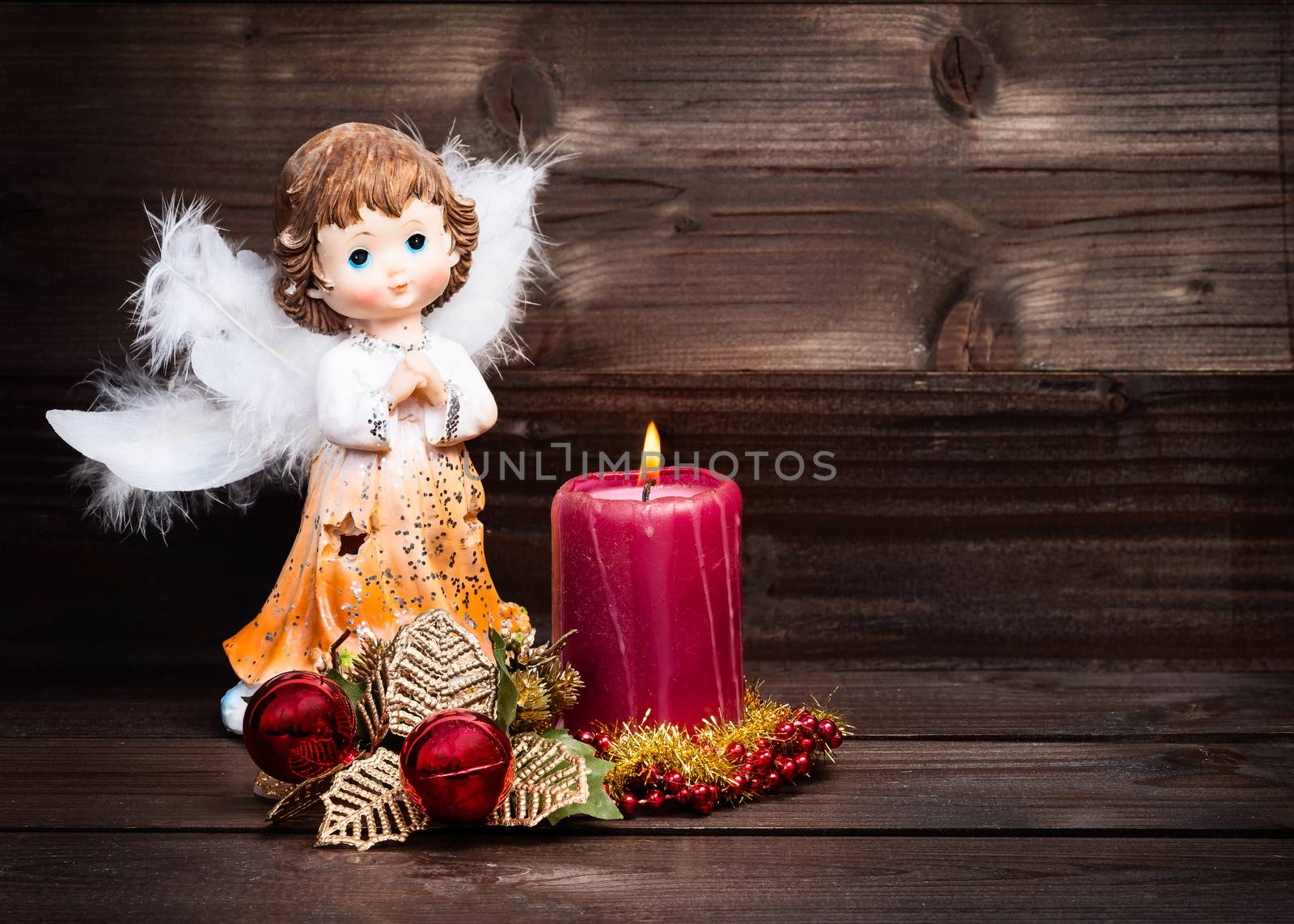 Christmas greeting card with candle and angels on wooden background.