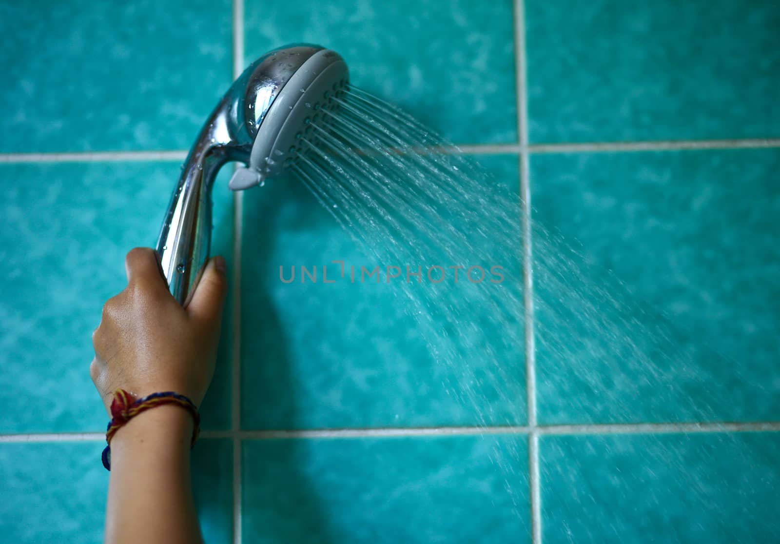 In the bathroom, a child holding a shower head
