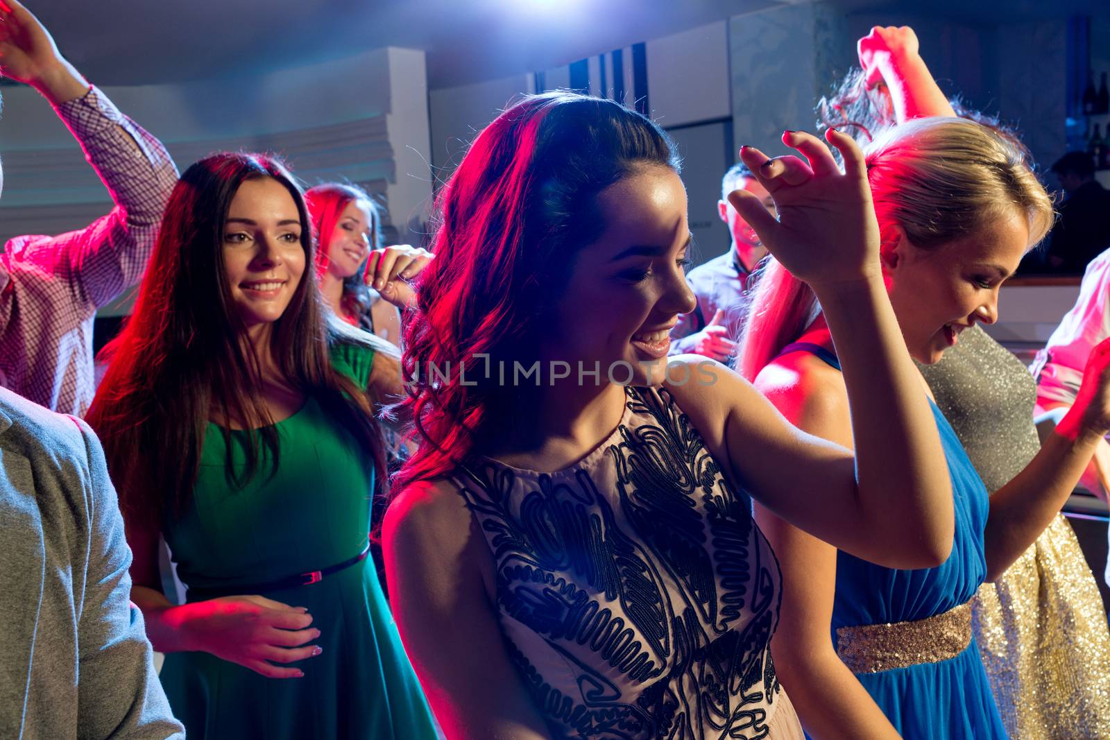 smiling friends dancing in club by dolgachov