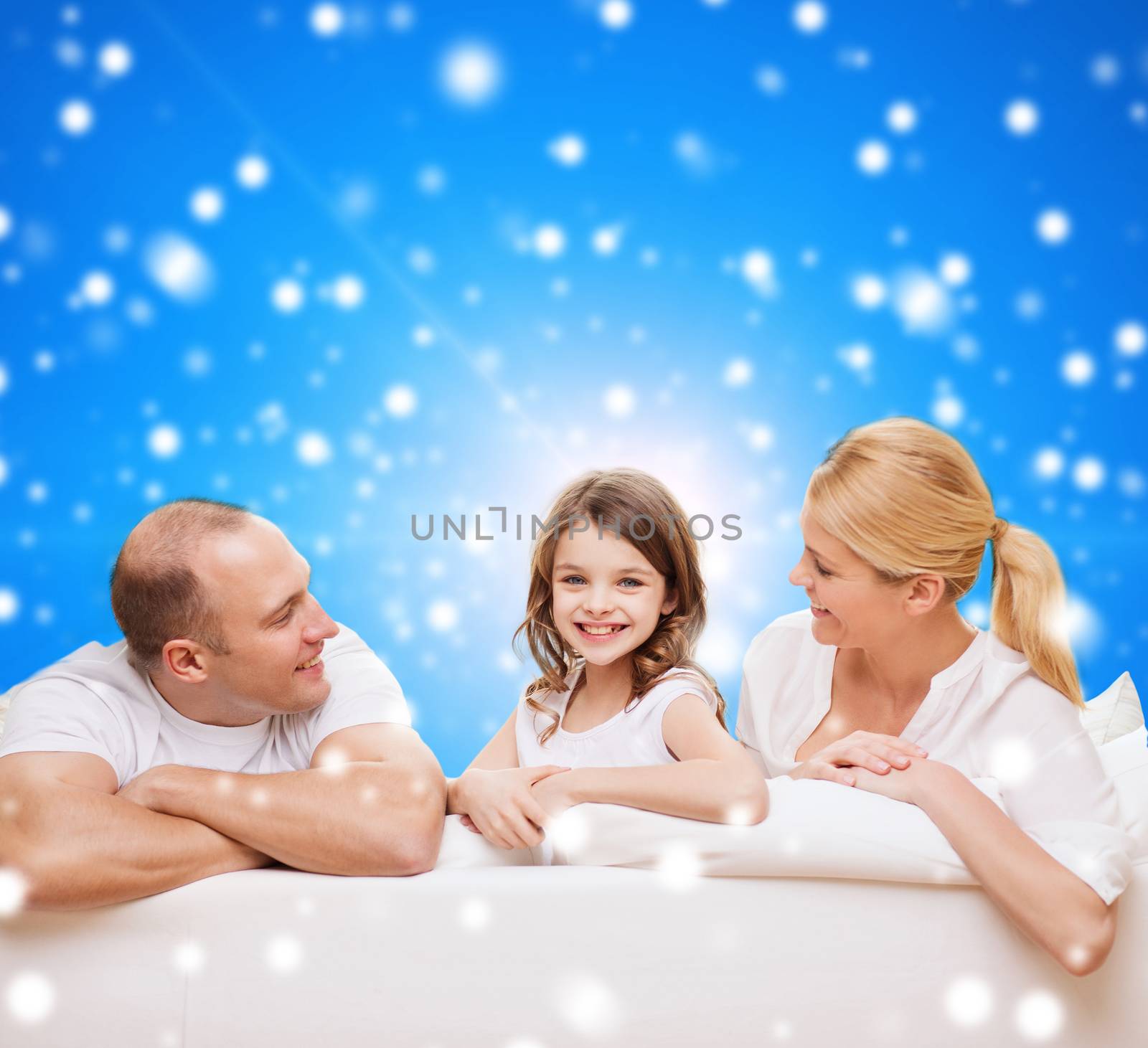 family, childhood, holidays and people - smiling mother, father and little girl over blue snowy background