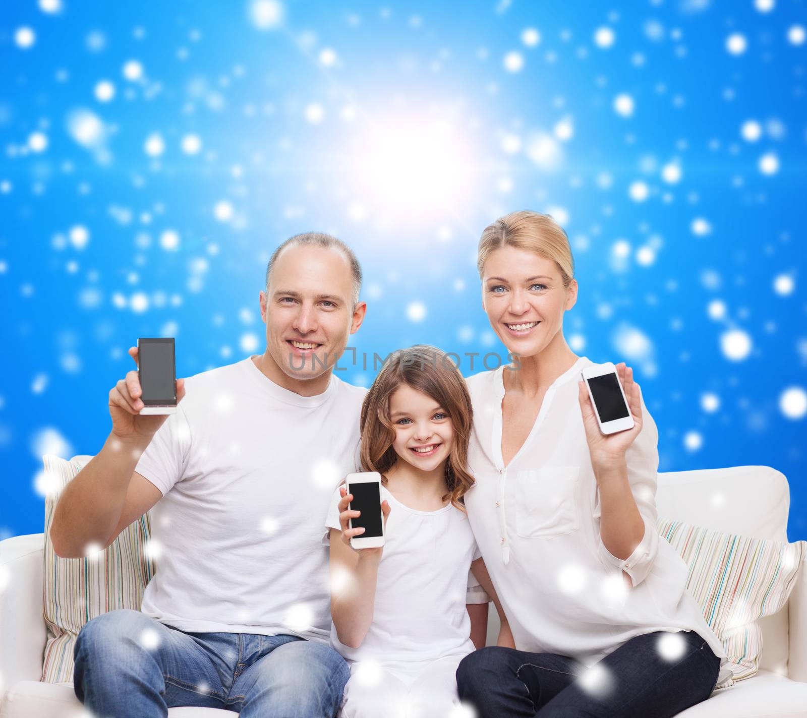 christmas, holidays, technology, advertisement and people concept - smiling family with smartphones over blue snowy background