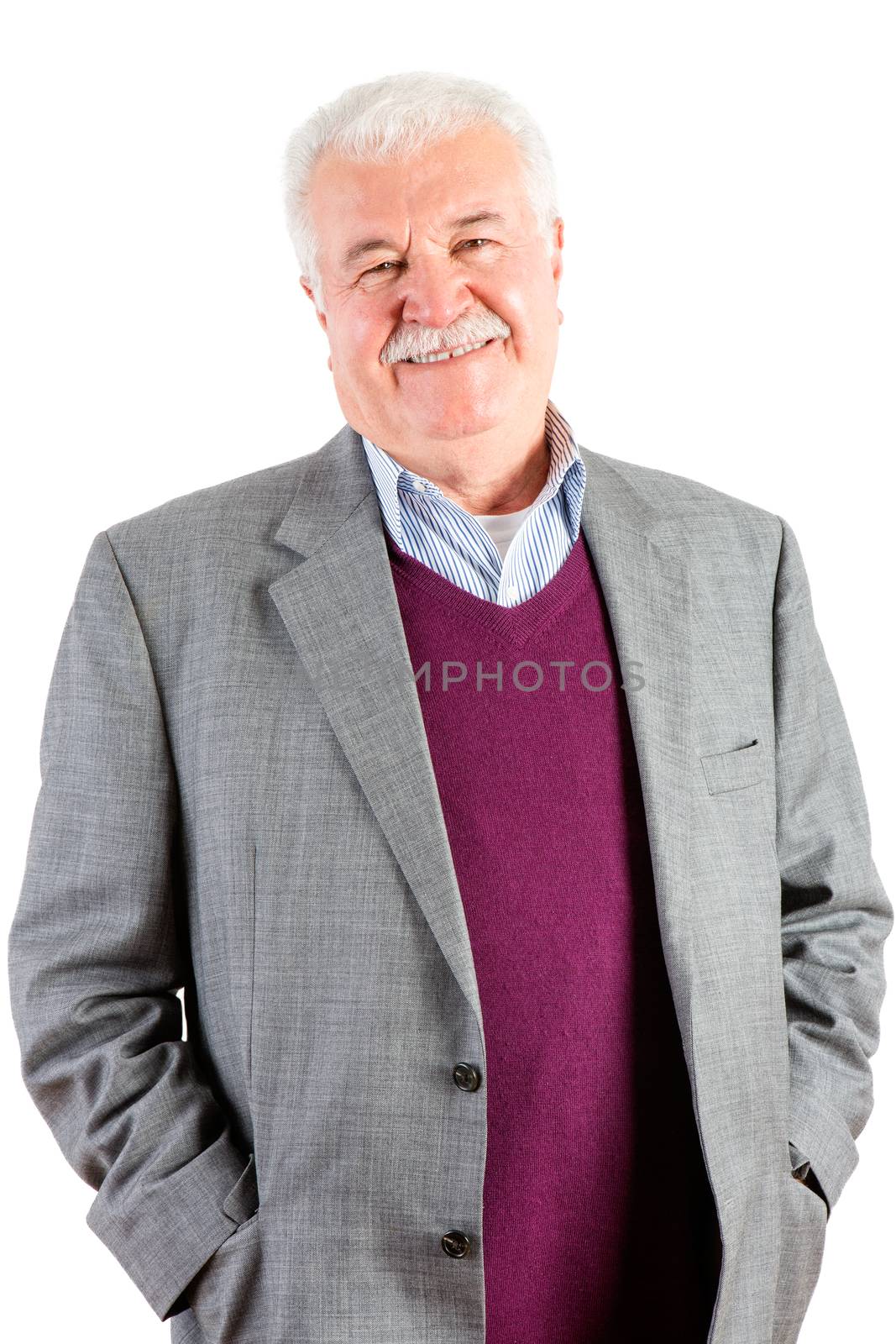 Jovial relaxed attractive senior man with white hair and a moustache standing with his hands in his pockets smiling at the camera, isolated on white