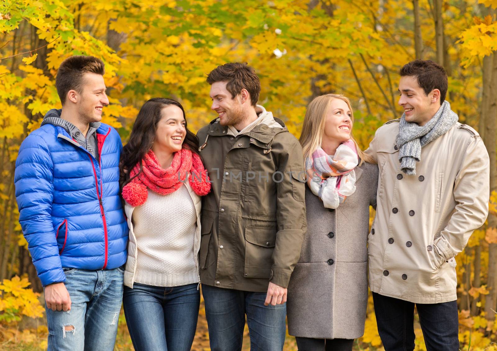 group of smiling men and women in autumn park by dolgachov