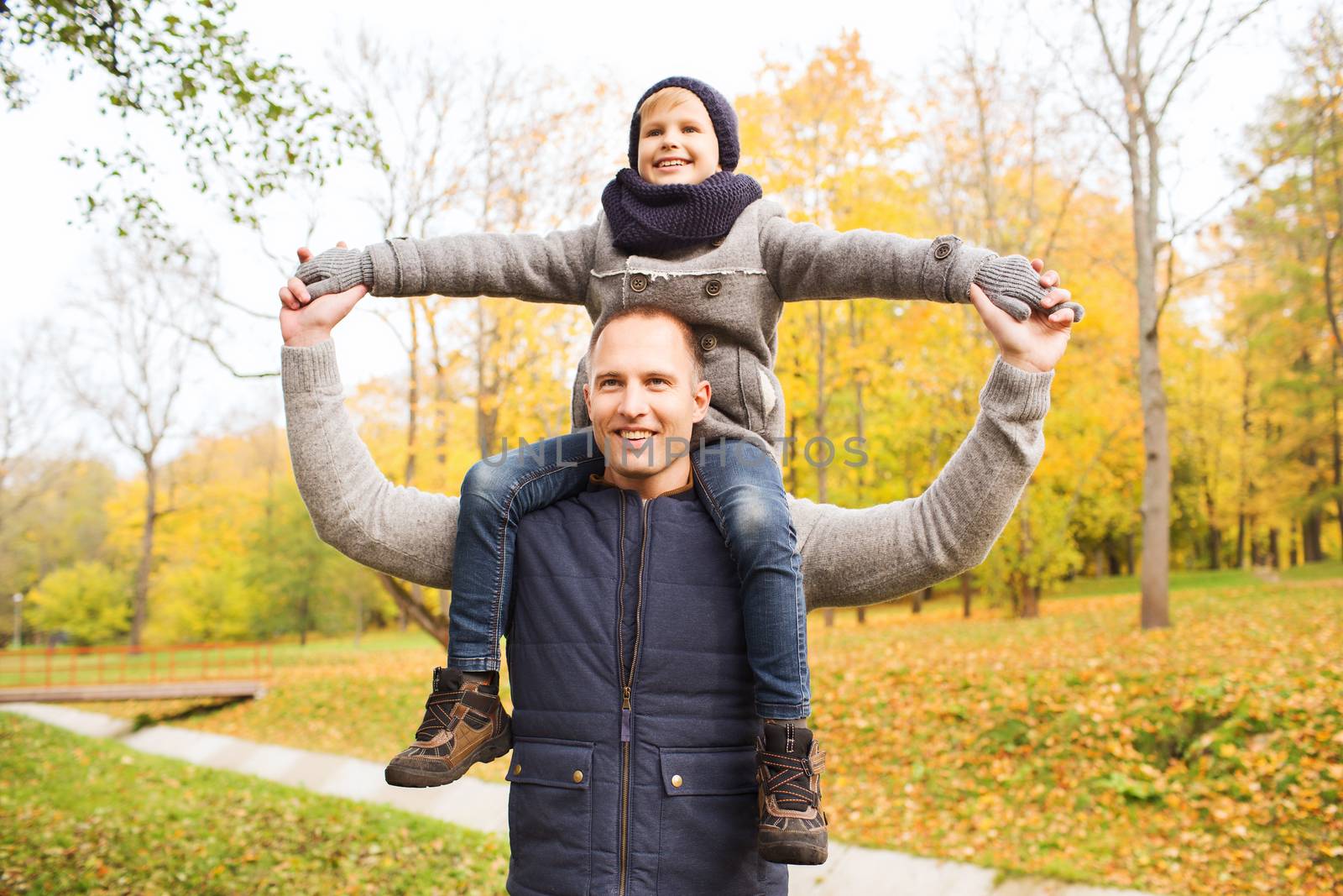 family, childhood, season and people concept - happy father and son having fun in autumn park