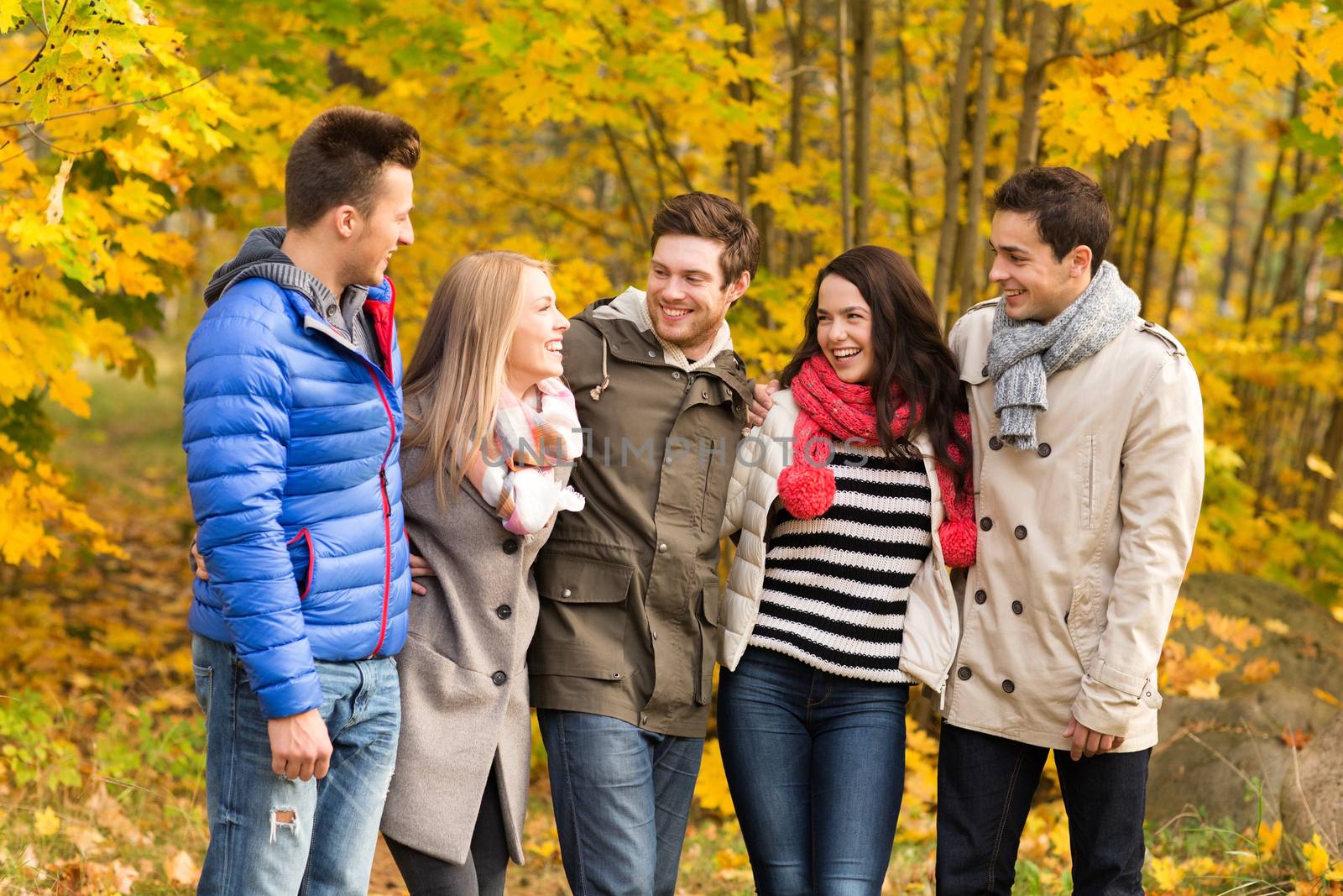 group of smiling men and women in autumn park by dolgachov