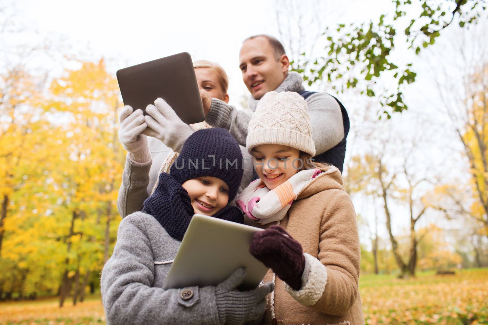 family, childhood, season, technology and people concept - happy family with tablet pc computers in autumn park