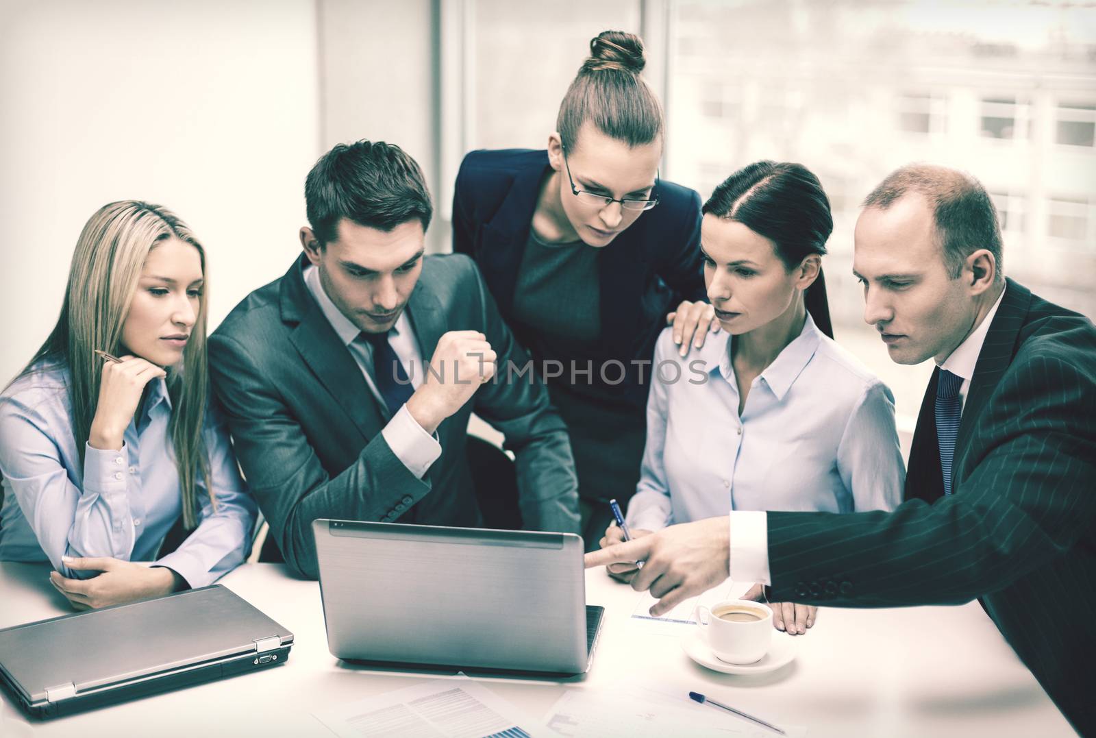 business, technology and office concept - serious business team with laptop computers, documents and coffee having discussion in office