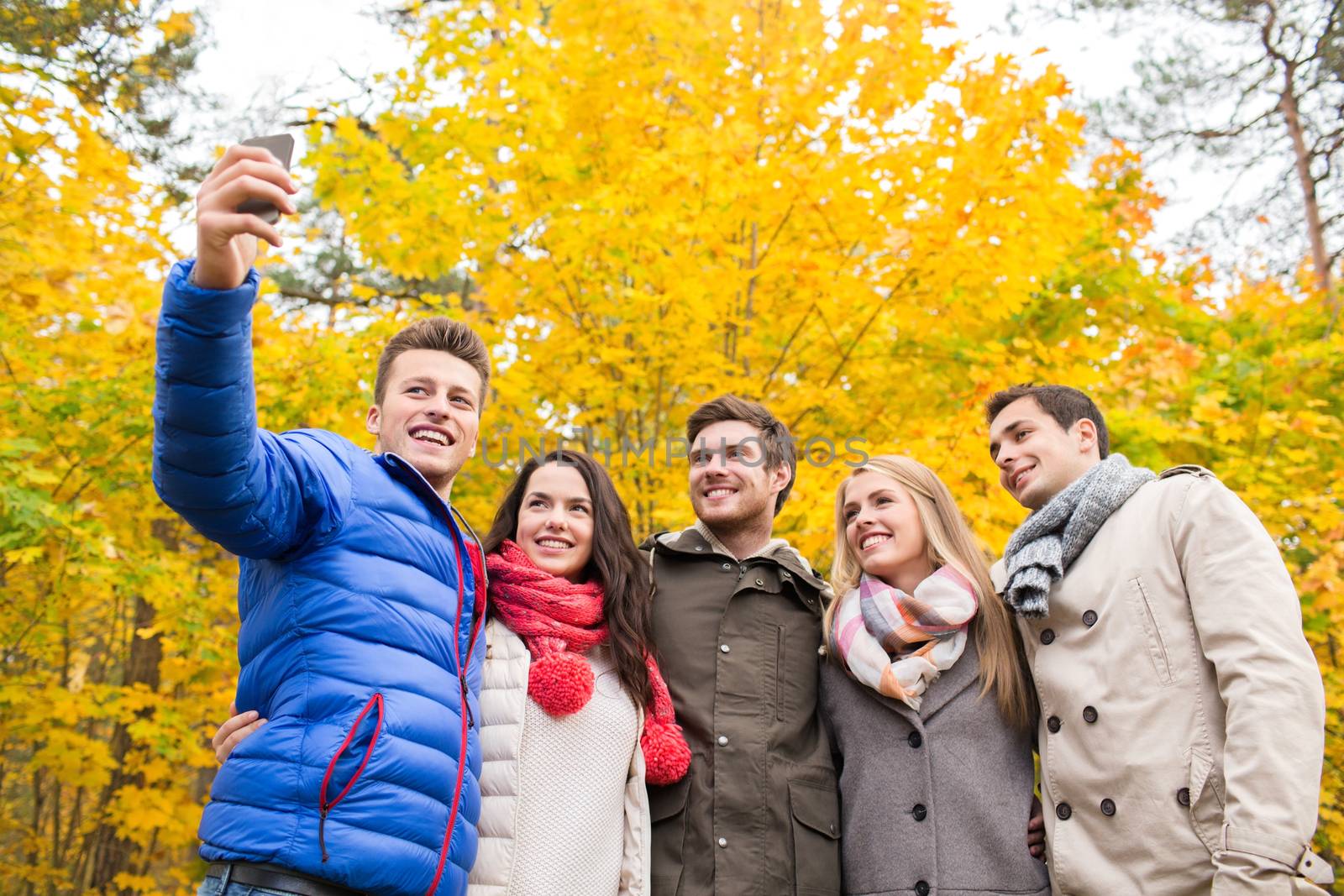 smiling friends with smartphone in city park by dolgachov