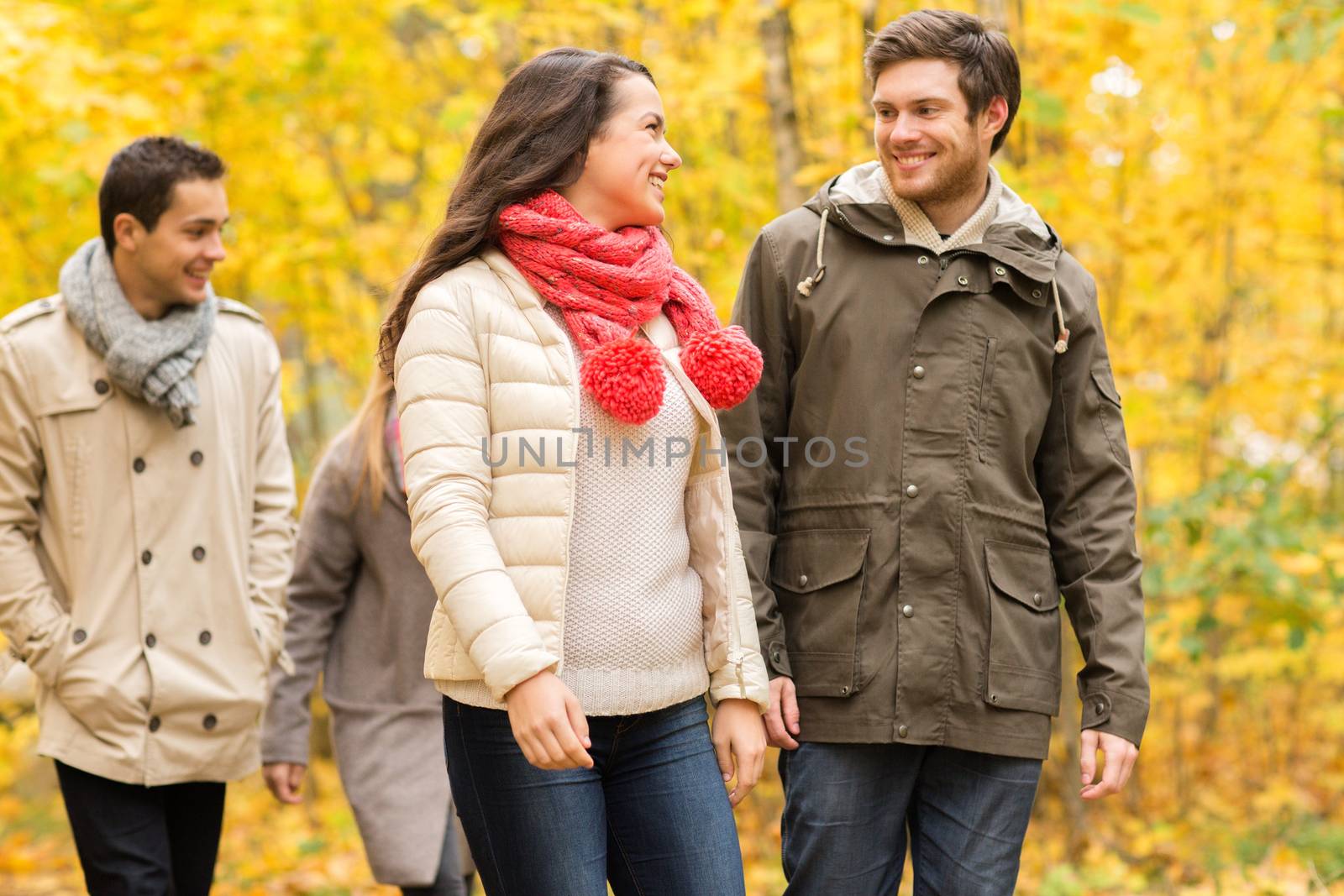 group of smiling men and women in autumn park by dolgachov