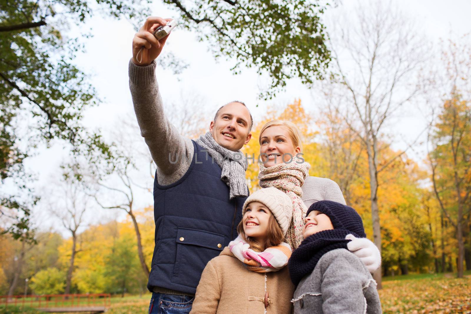 happy family with camera in autumn park by dolgachov