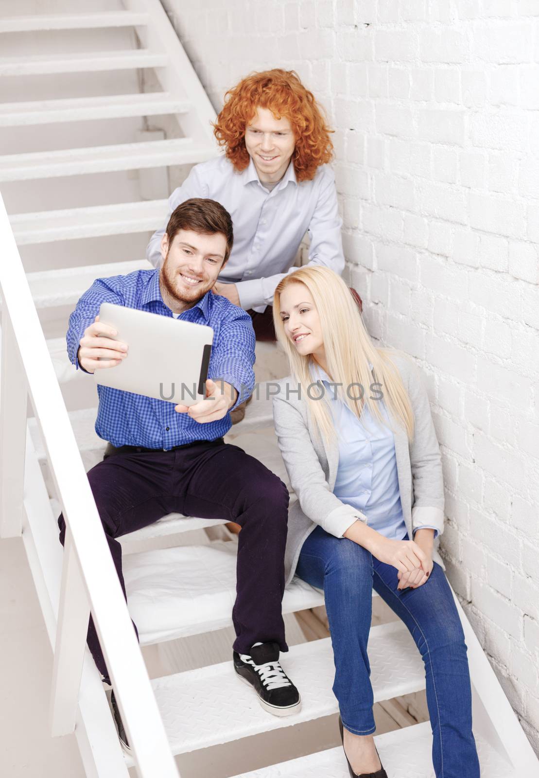 team with tablet pc computer sitting on staircase by dolgachov