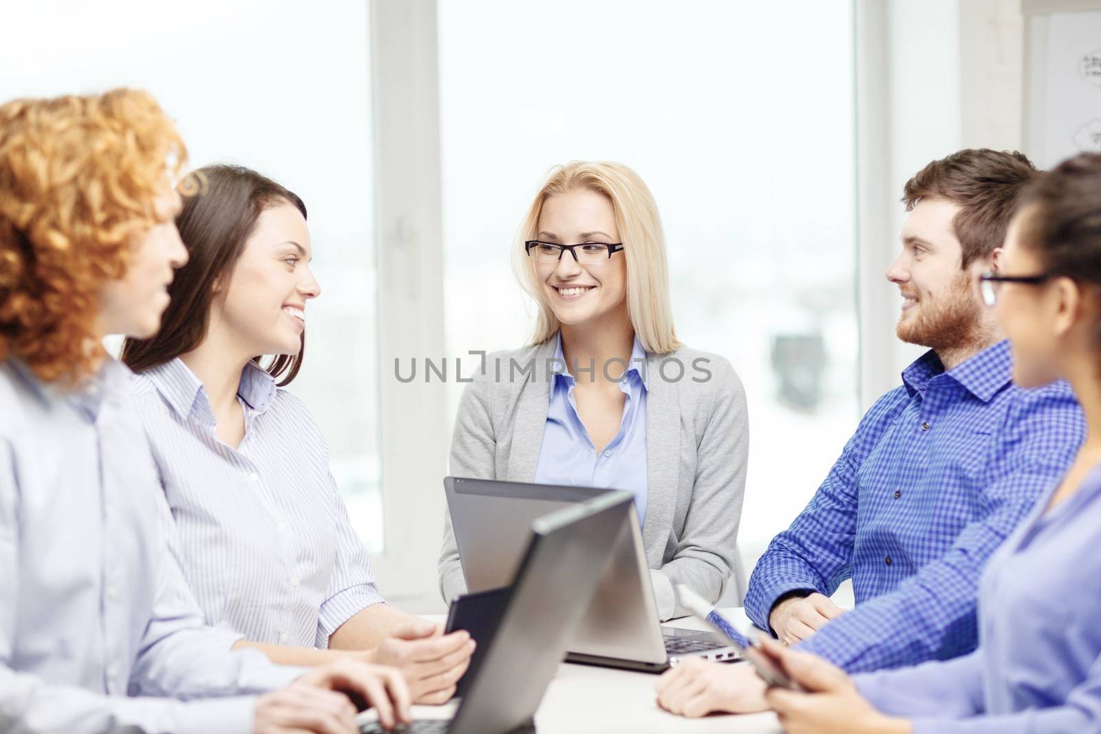 business, office and startup concept - smiling creative team with table pc and laptop computers working in office