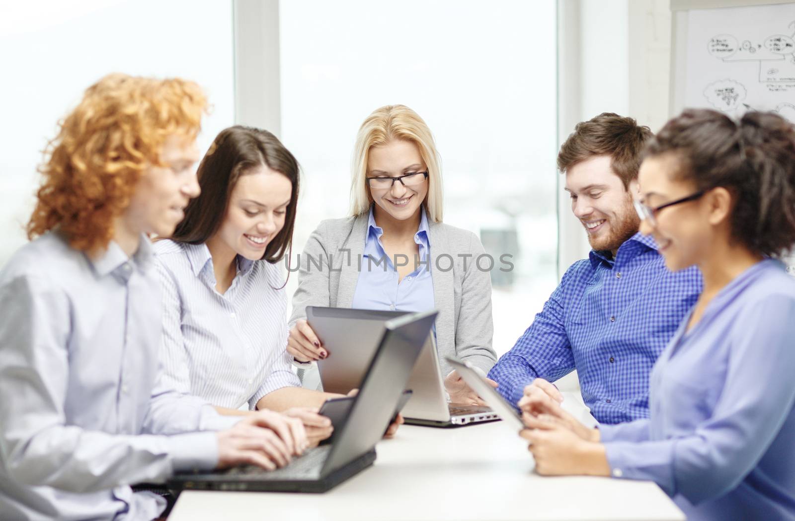 smiling team with laptop and table pc computers by dolgachov