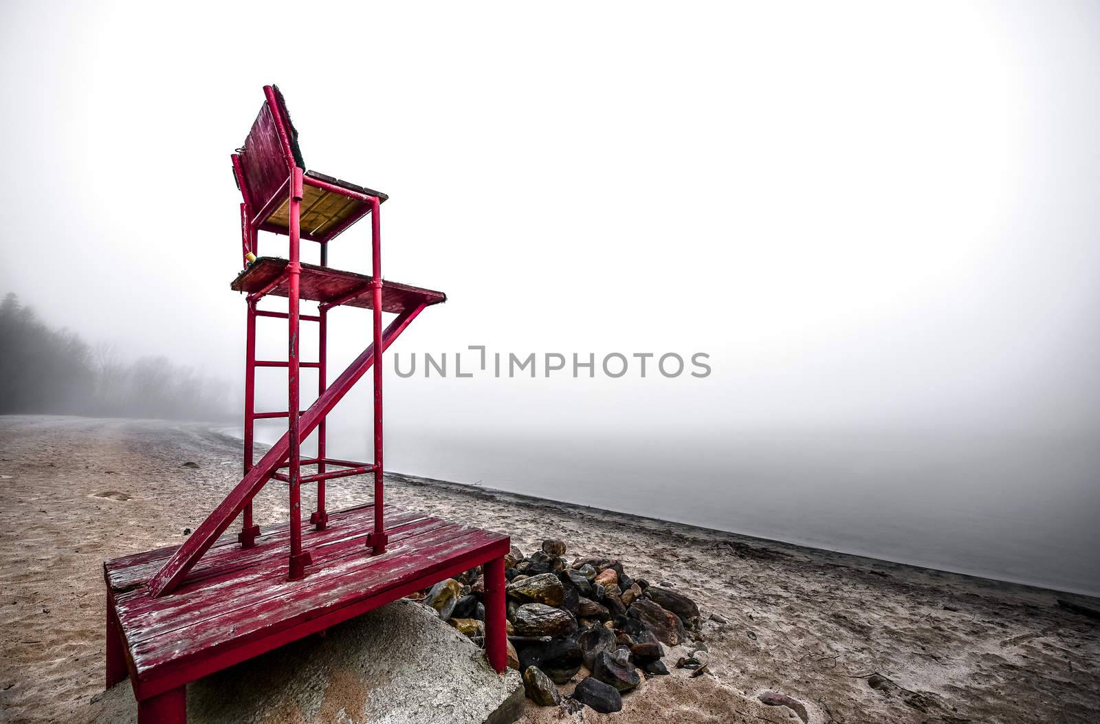 A lonely lifeguard seat stands empty in the fog on a November beach in Ontario Canada.