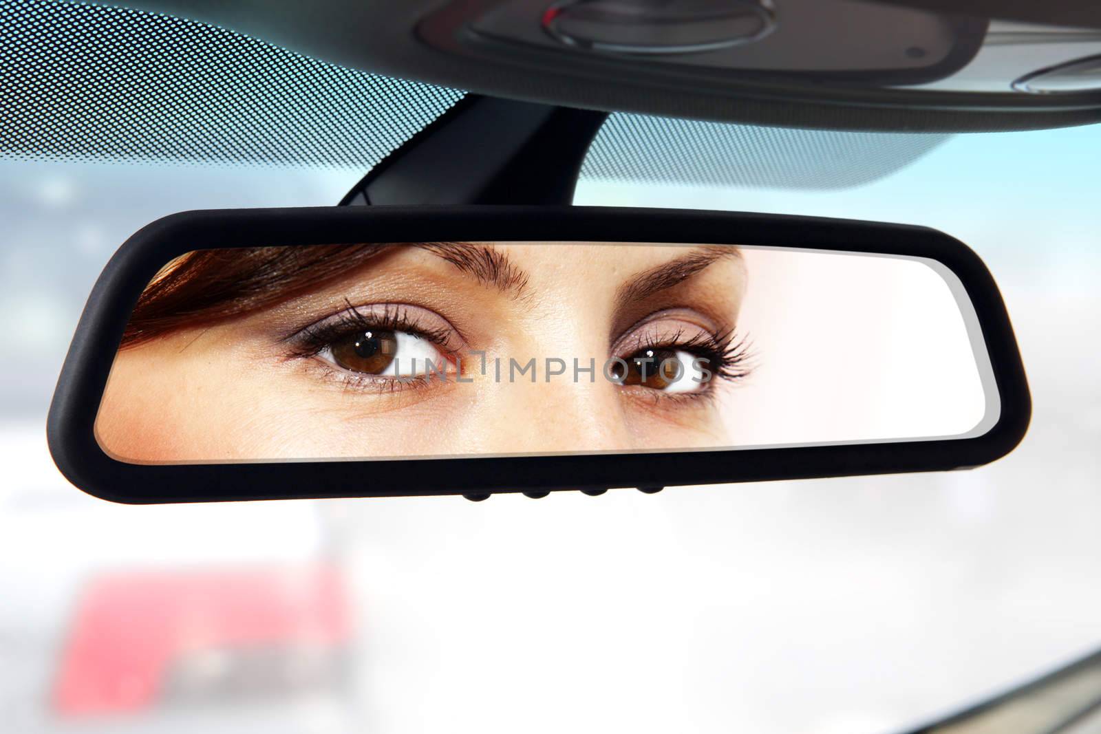 woman sits on driver's seat and Looks in the rear-view mirror