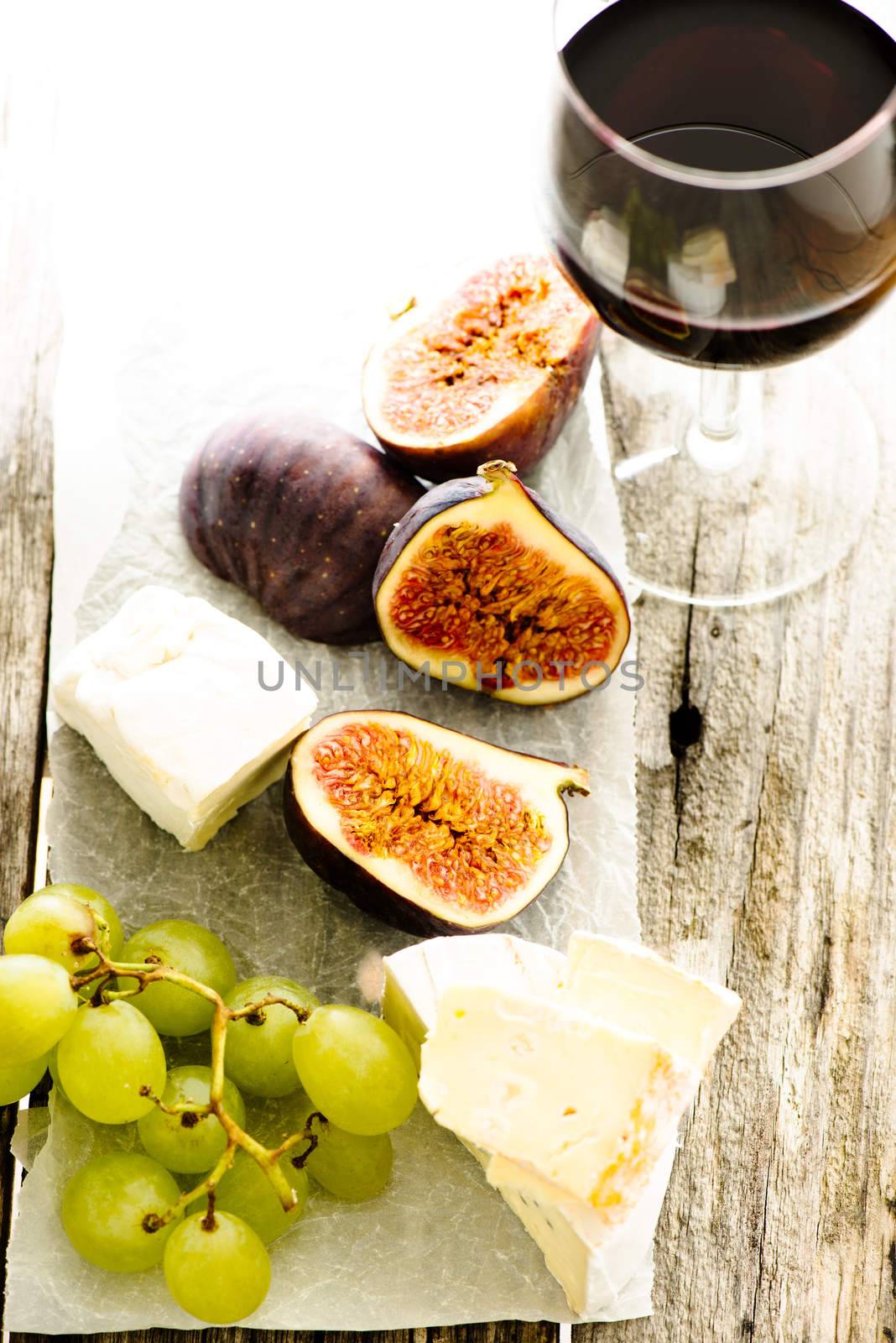 Figs, grape, cheese and glass of wine on wooden table
