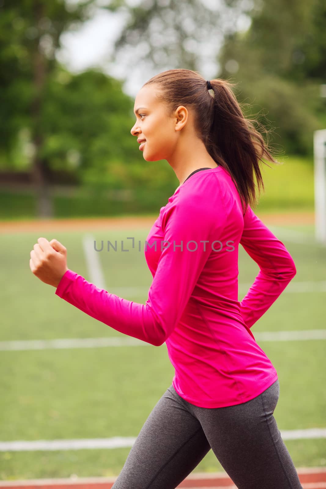 smiling woman running on track outdoors by dolgachov