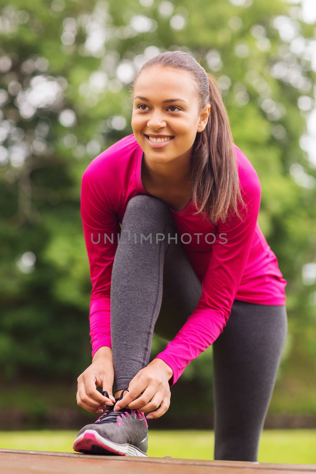 sport, exercise, park and lifestyle concept - smiling african american woman exercising outdoors