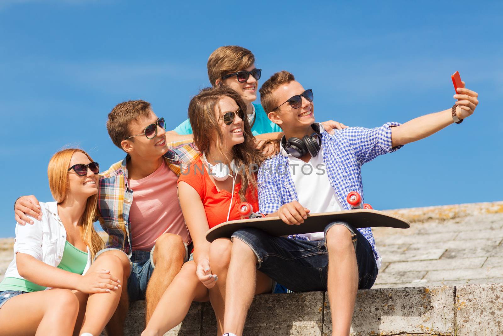 group of smiling friends with smartphone outdoors by dolgachov