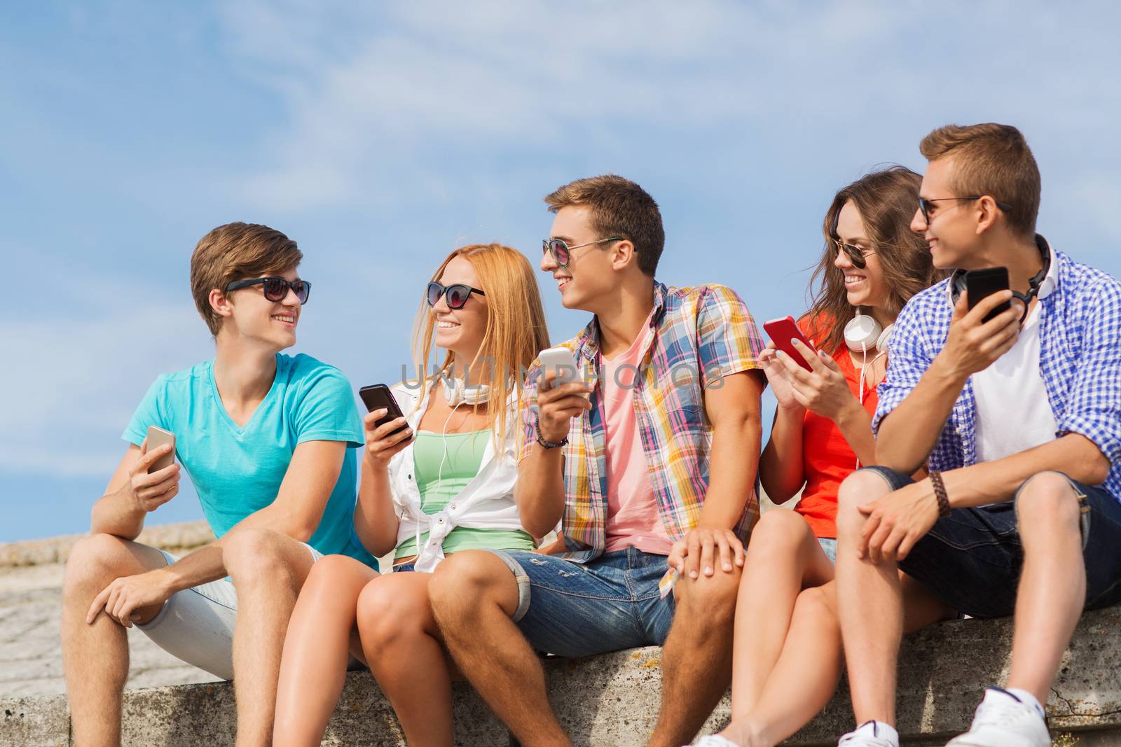 group of smiling friends with smartphones outdoors by dolgachov