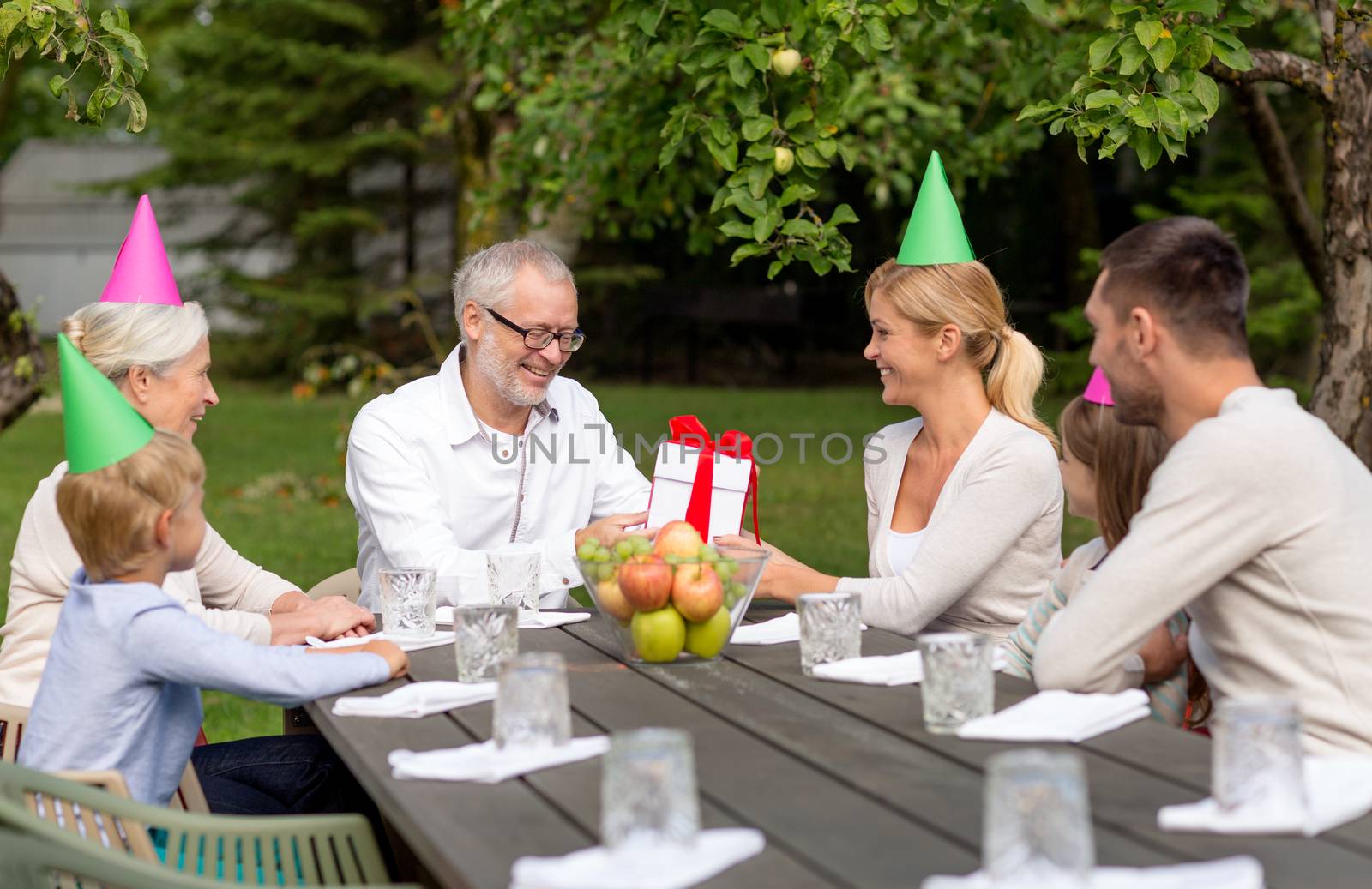 family, happiness, generation, home and people concept - happy family with gift box having holiday dinner outdoors