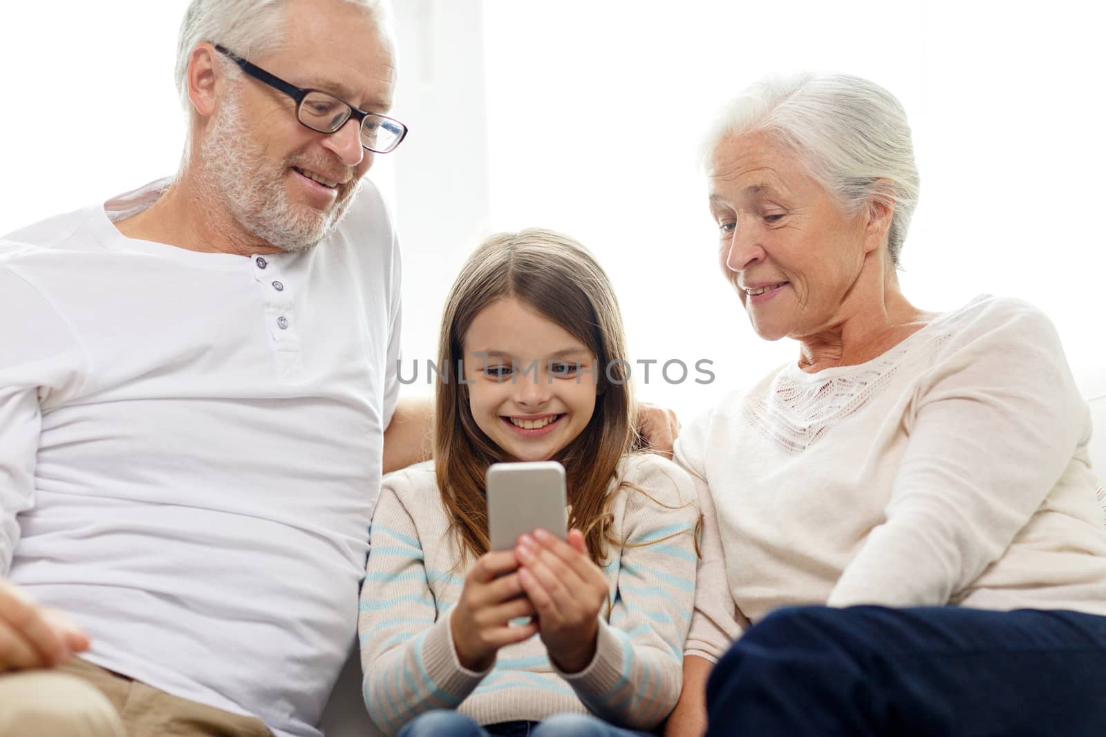 smiling family with smartphone at home by dolgachov