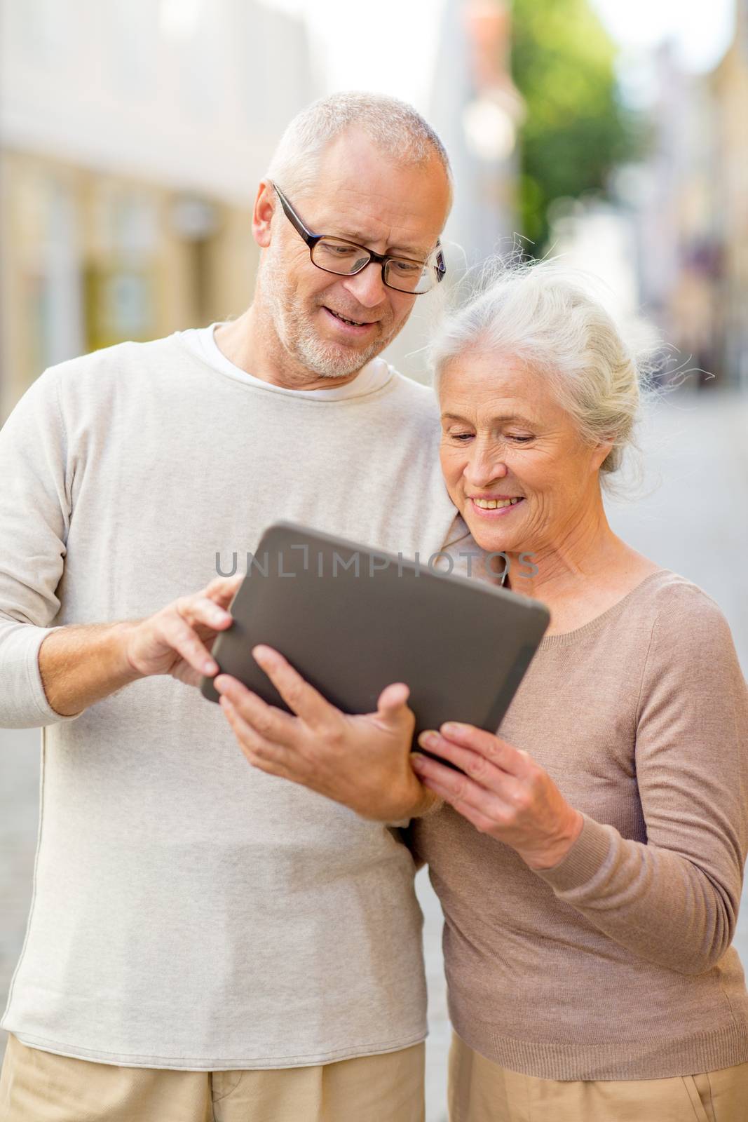 age, tourism, travel, technology and people concept - senior couple with tablet pc computer on street