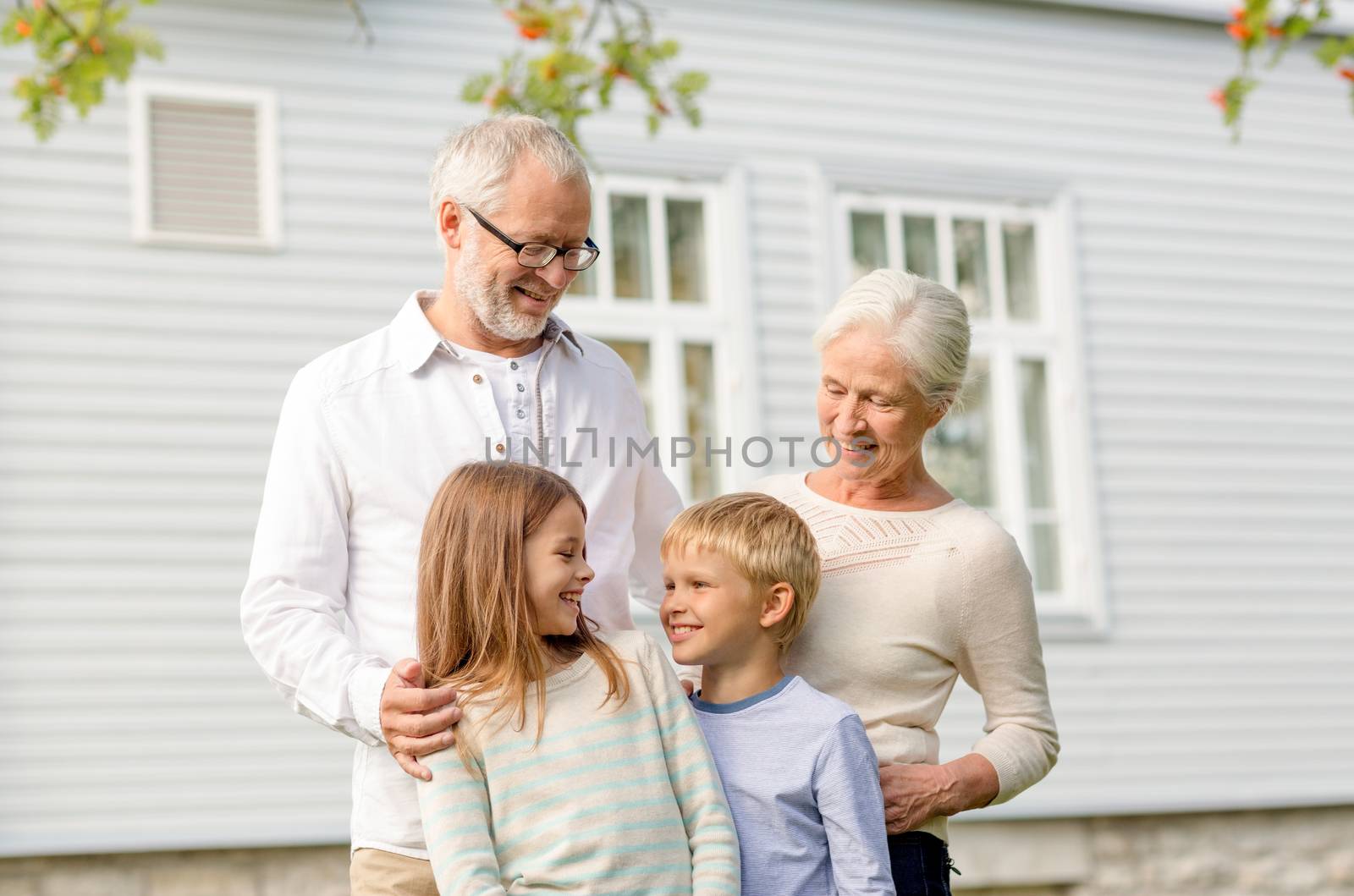 family, happiness, generation, home and people concept - happy family standing in front of house outdoors