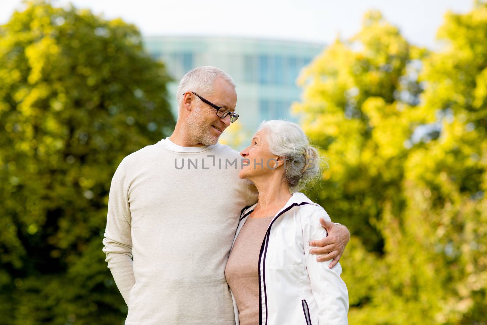 family, age, tourism, travel and people concept - senior couple hugging in city park