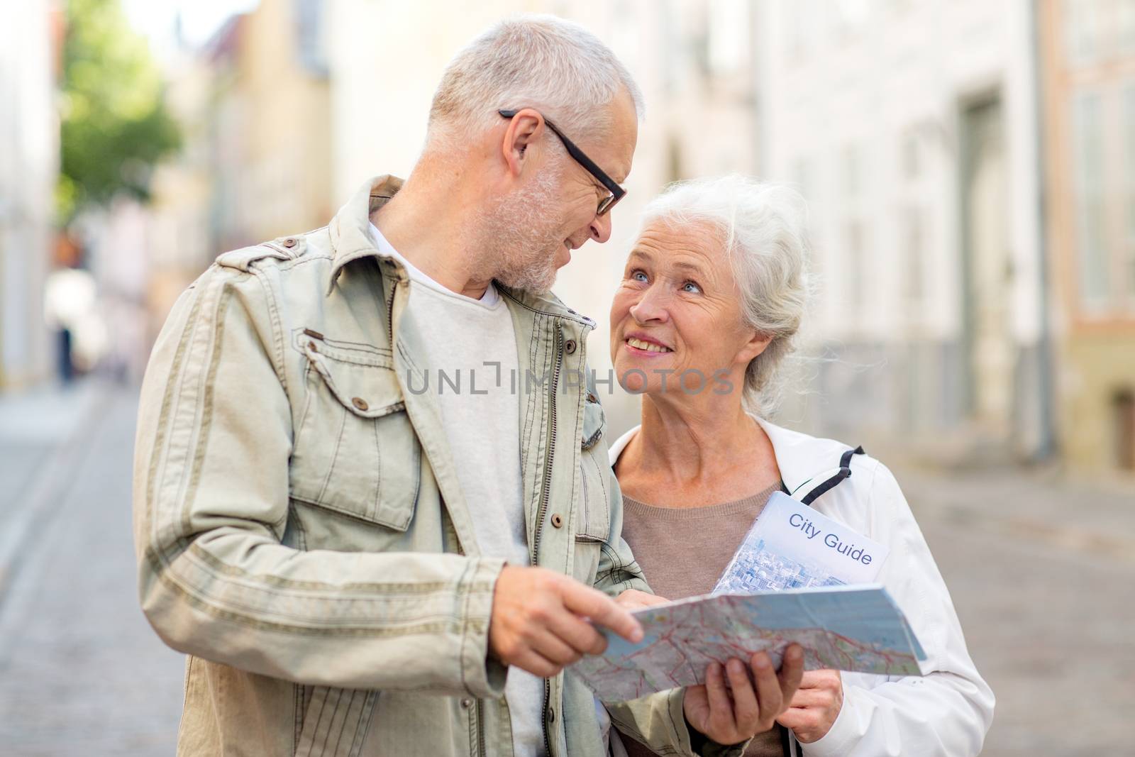 family, age, tourism, travel and people concept - senior couple with map and city guide on street