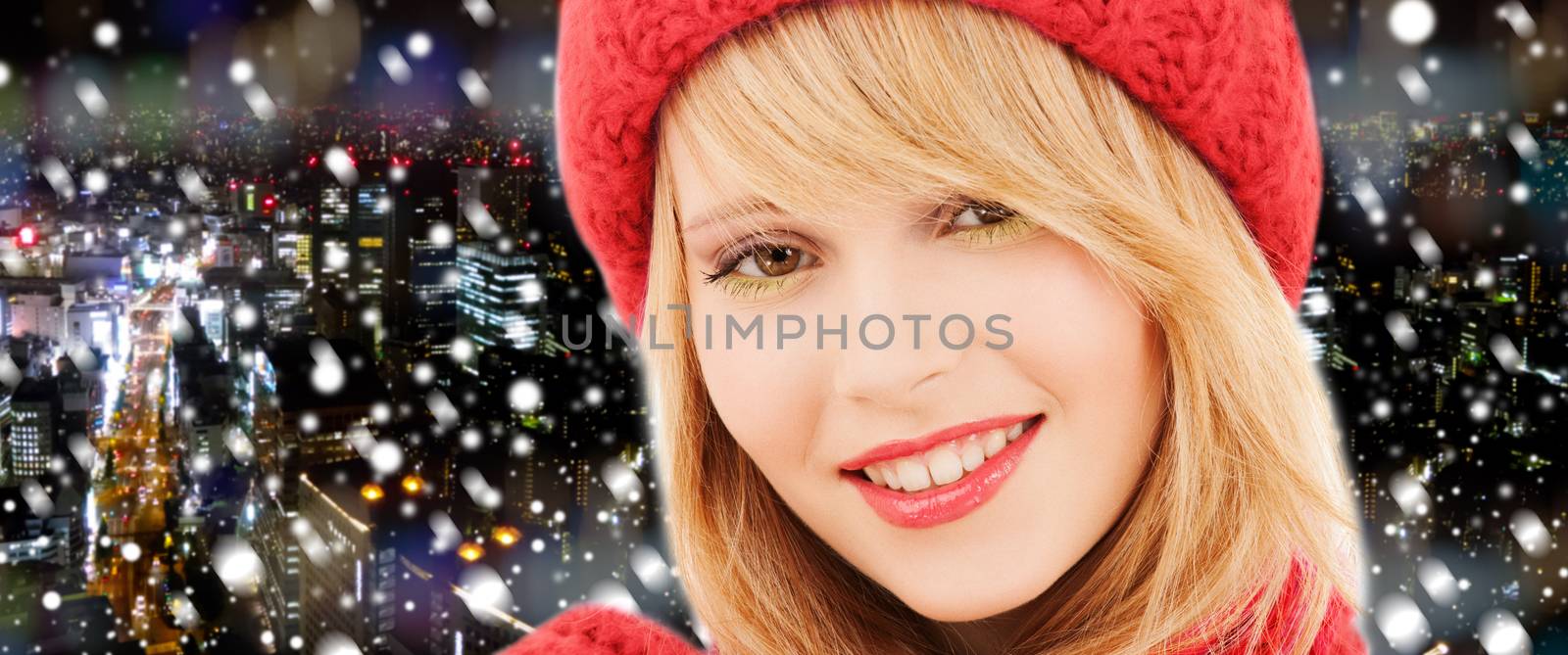 happiness, winter holidays, christmas and people concept - close up of smiling young woman in red hat and scarf over snowy night city background