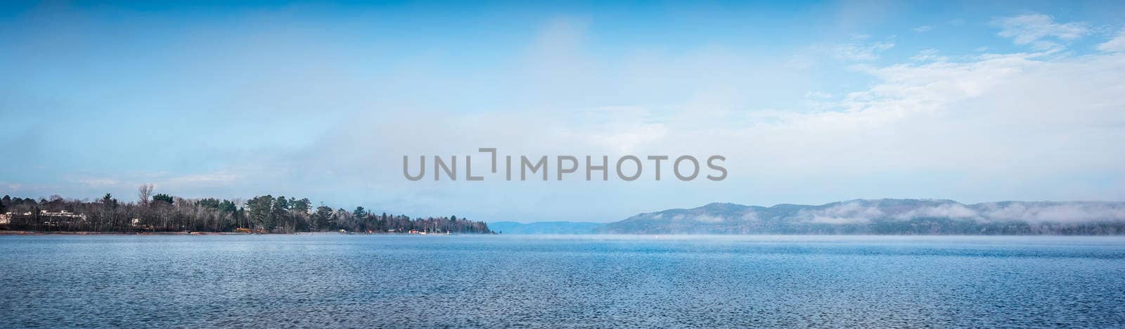 Fog rising from blue water into sky  - Panoramic fog lifting off the Ottawa River in late morning with Laurentian Hills and mountains -