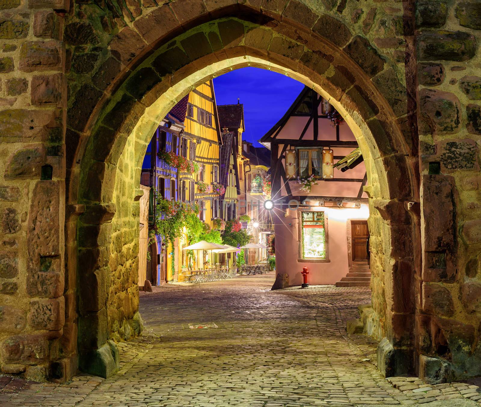 View of Riquewihr, Alsace, France, through city wall gate at night